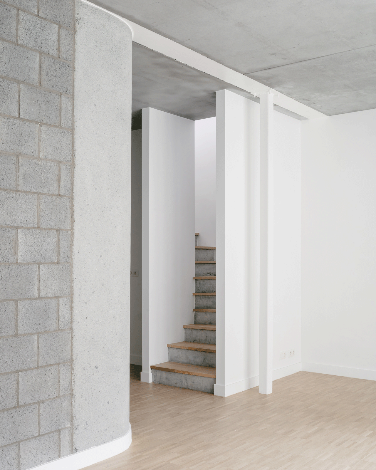 Interior stair beside exposed block walls and a concrete ceiling