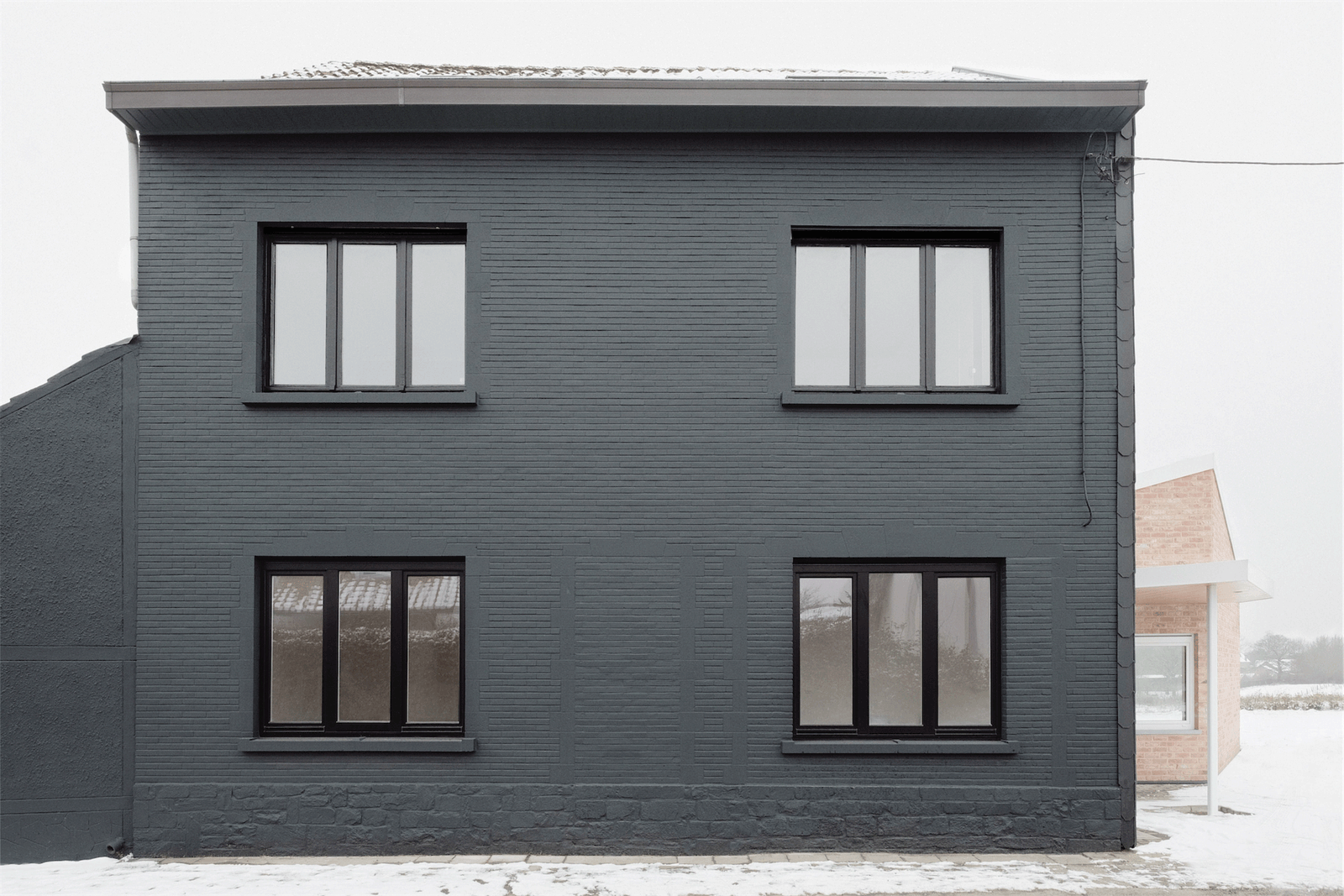 Dark-painted brick street façade with four regular windows