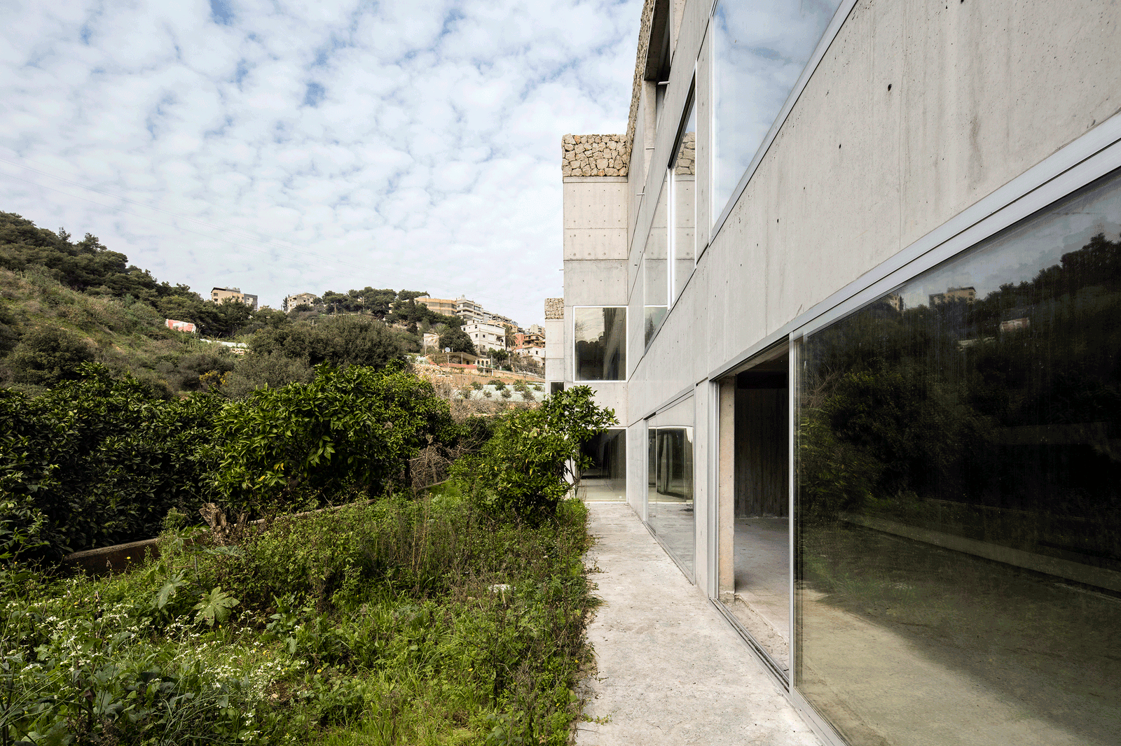 Garden path running beside the concrete and glass façade