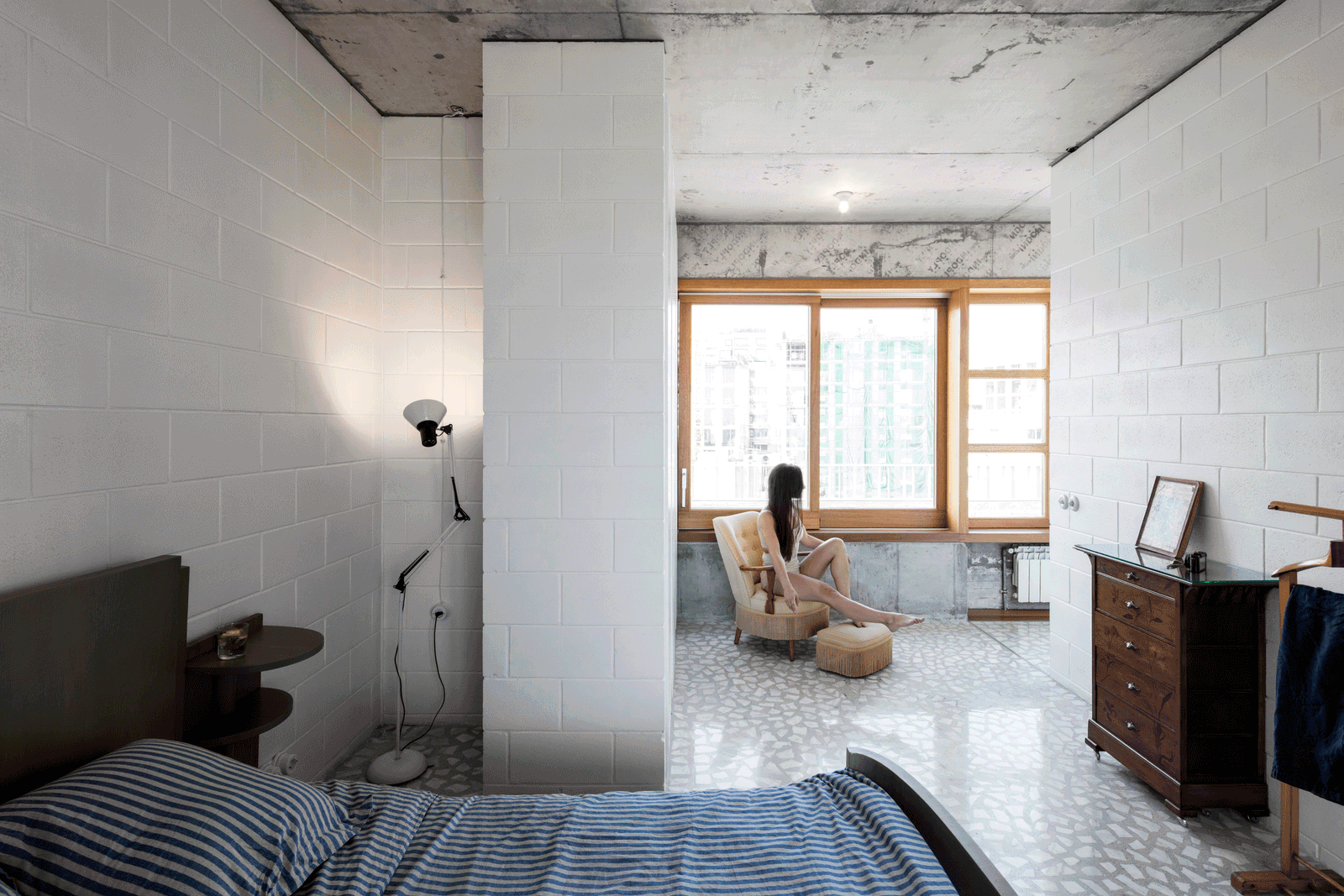 Bedroom opening through a white partition to the living space