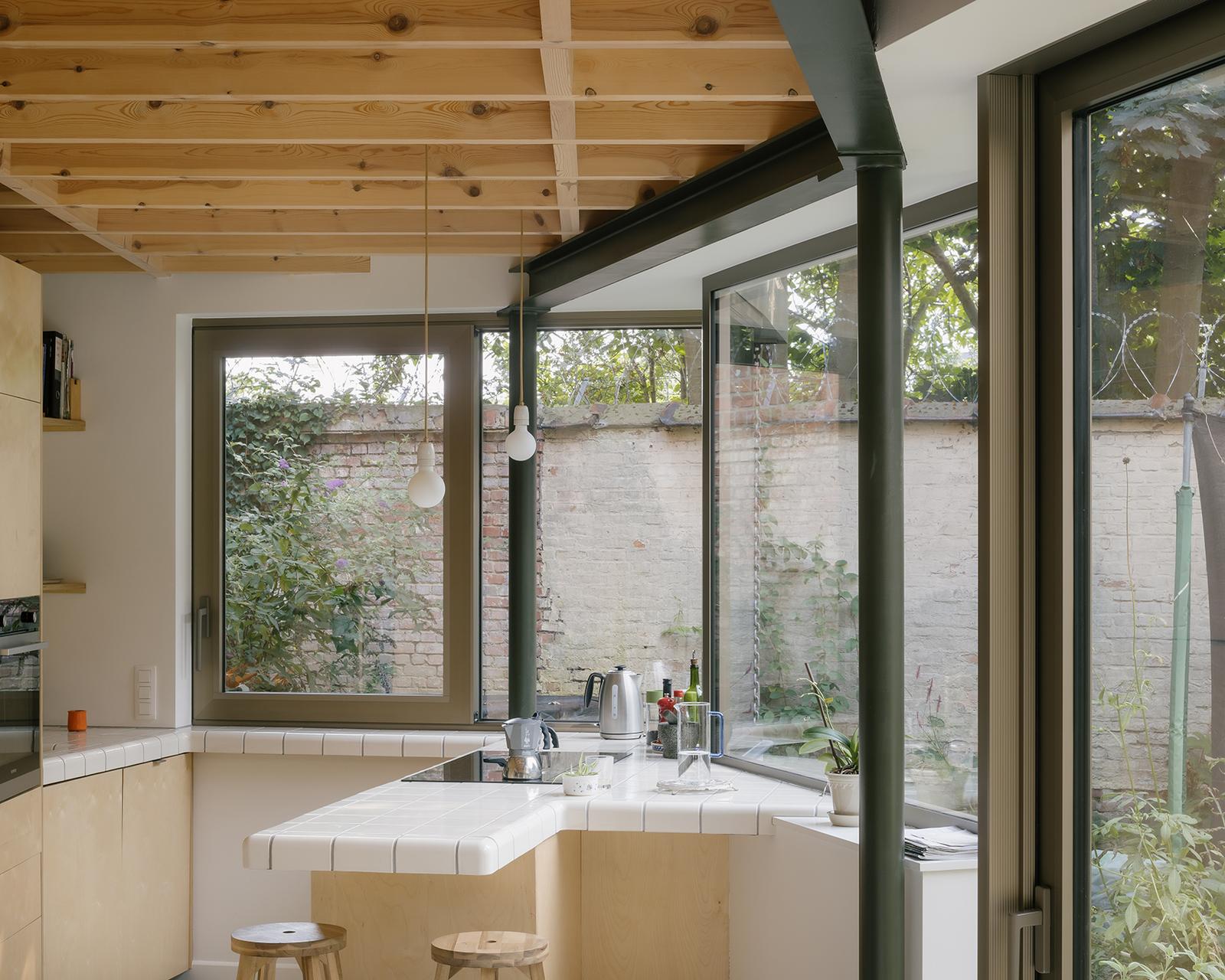 Kitchen sink set beneath corner windows and a timber ceiling