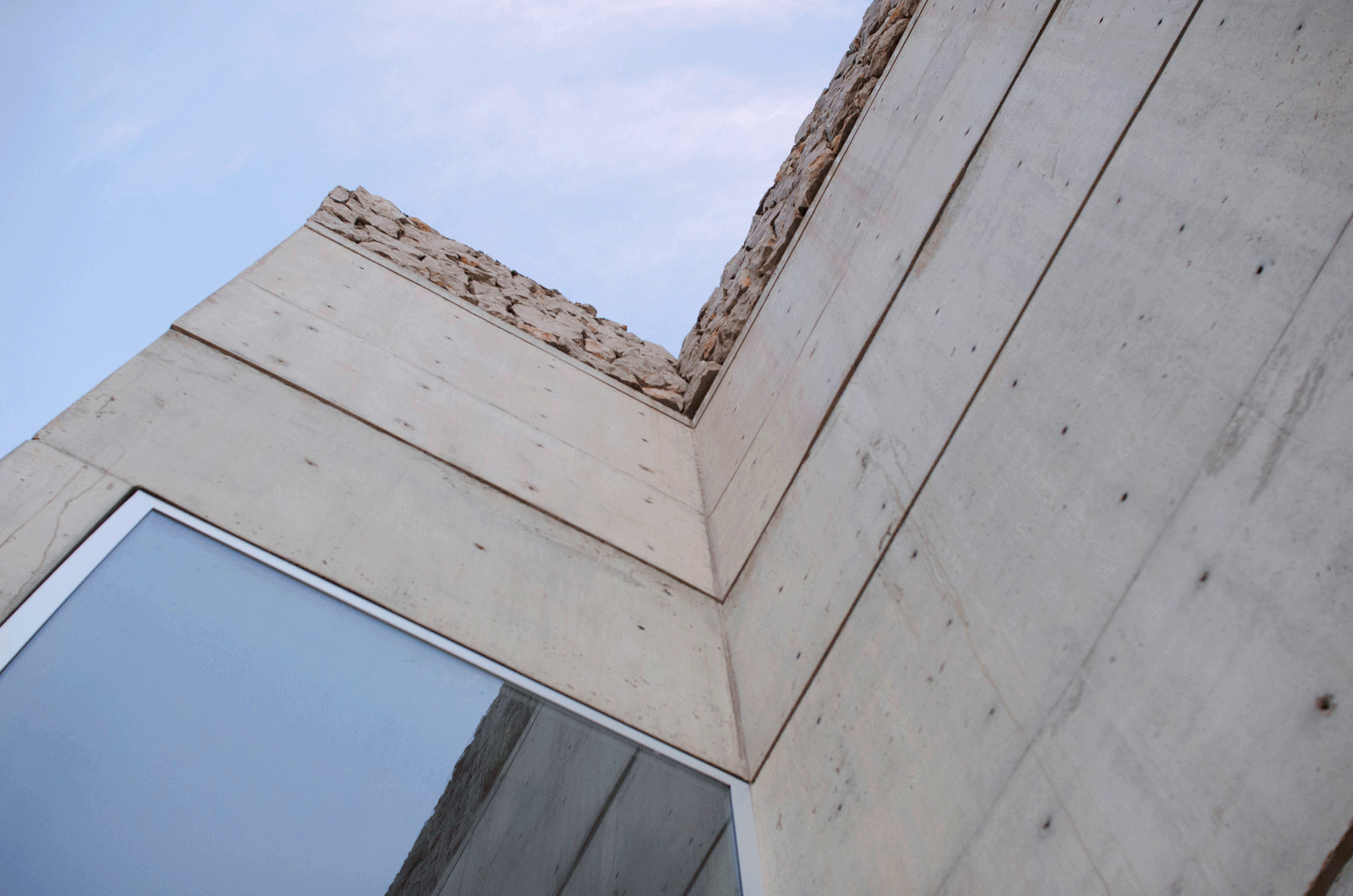 Upward view of an angular opening between board-marked concrete walls