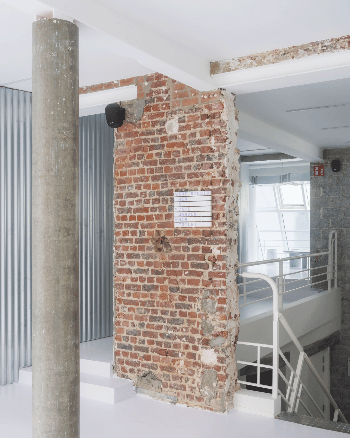 Concrete column and retained brick wall beneath the white mezzanine