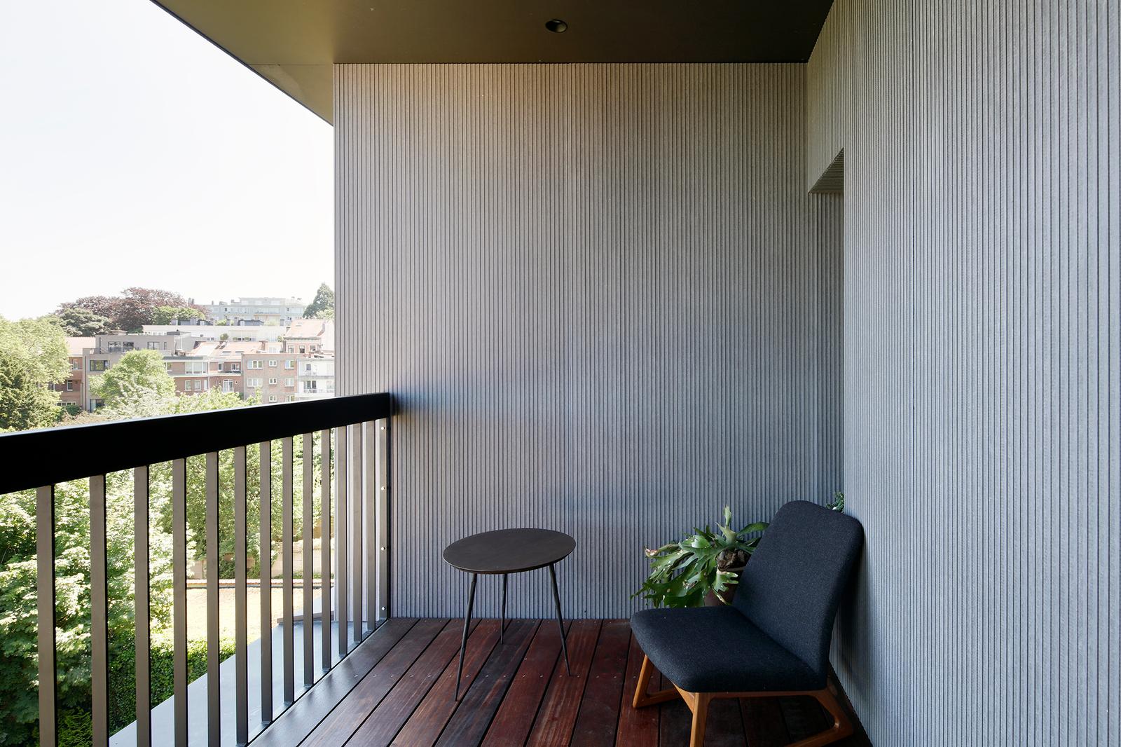 Covered balcony with dark railing and vertically lined walls