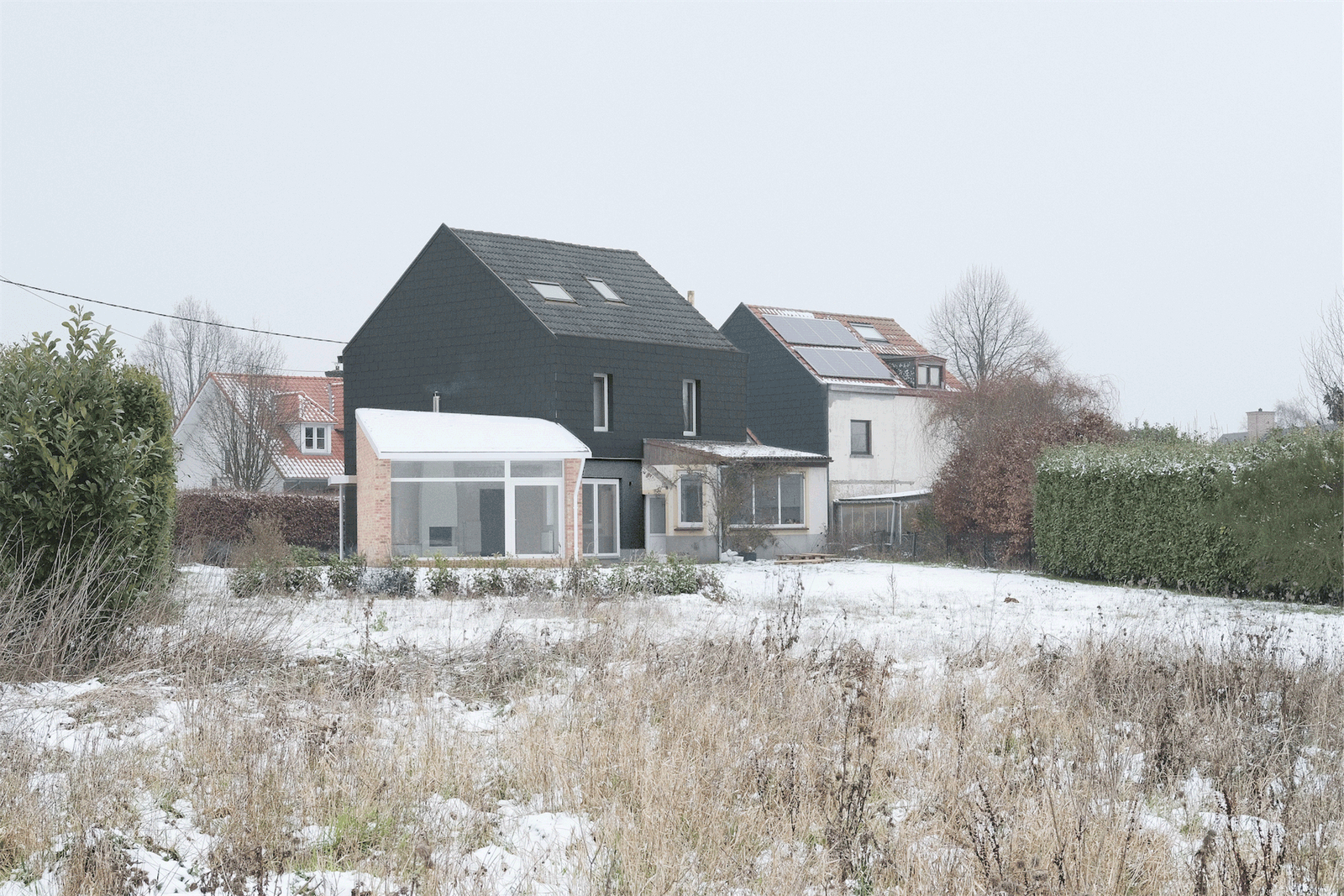 Rear view of the dark gabled house and low brick extension