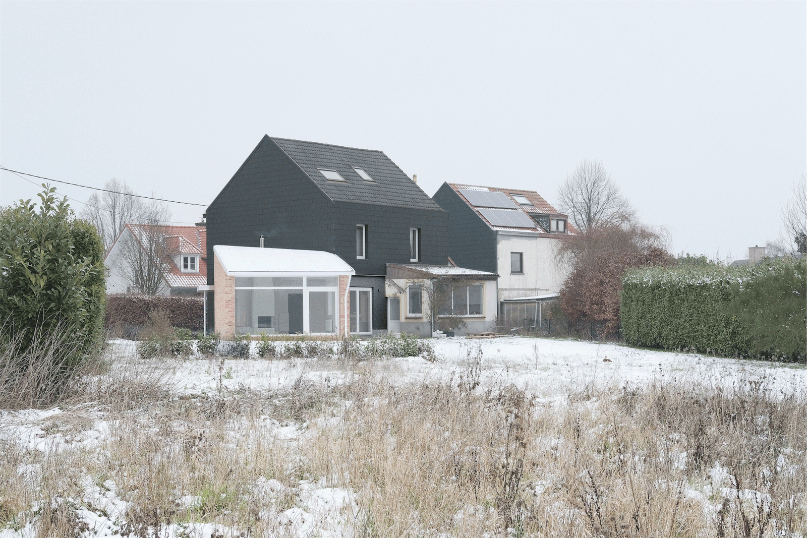 Rear view of the dark gabled house and low brick extension
