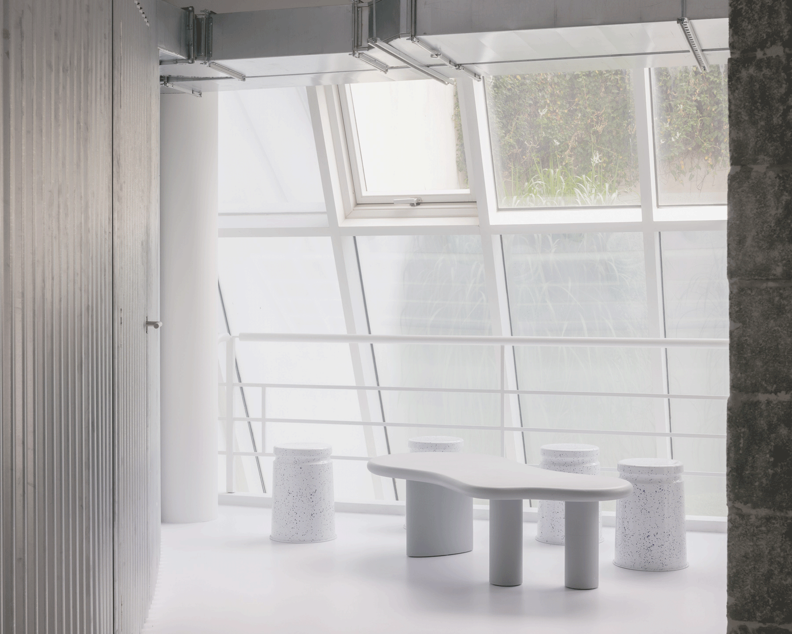 White lounge with low tables beneath a row of roof windows