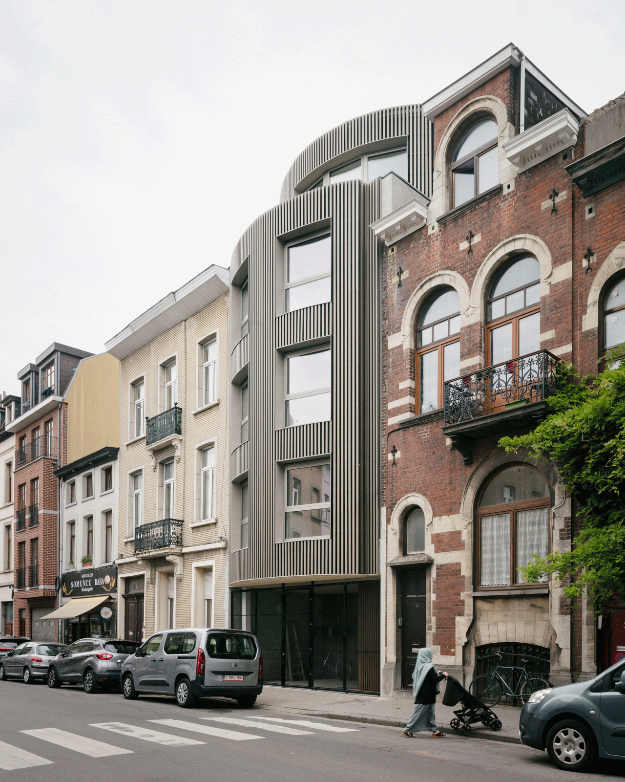 Rounded infill building with vertical slats on a dense city street