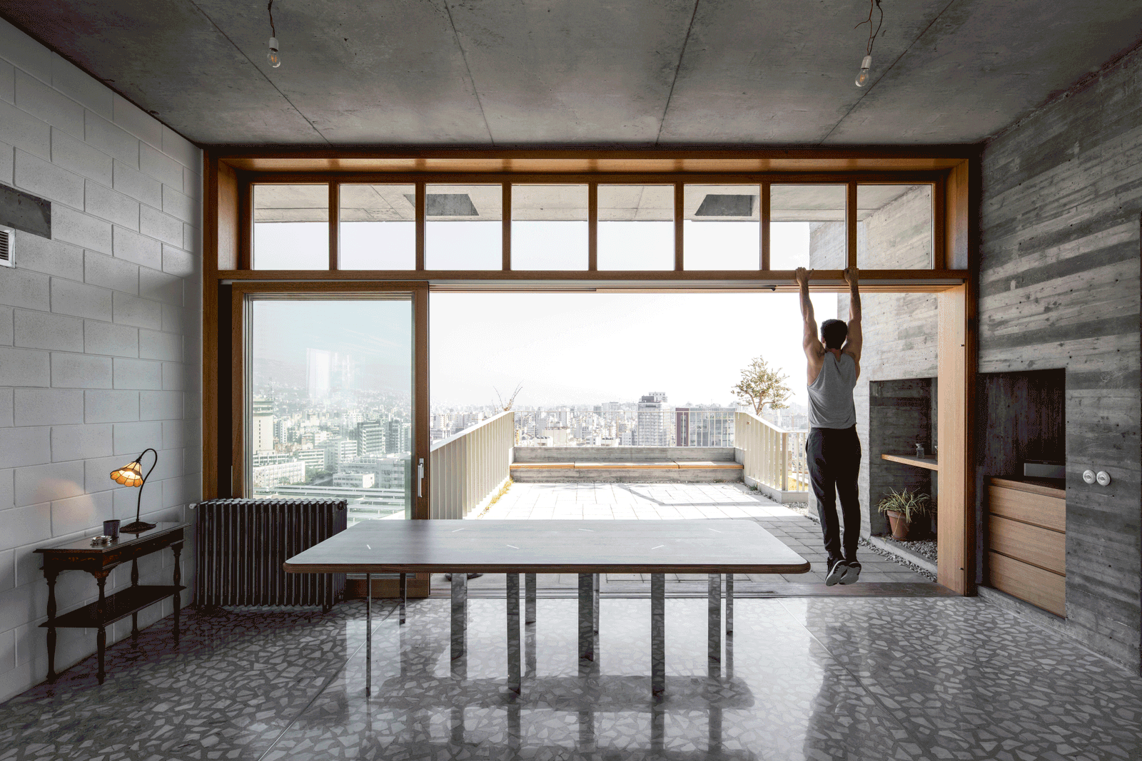 Dining table facing an open terrace through full-width glazing
