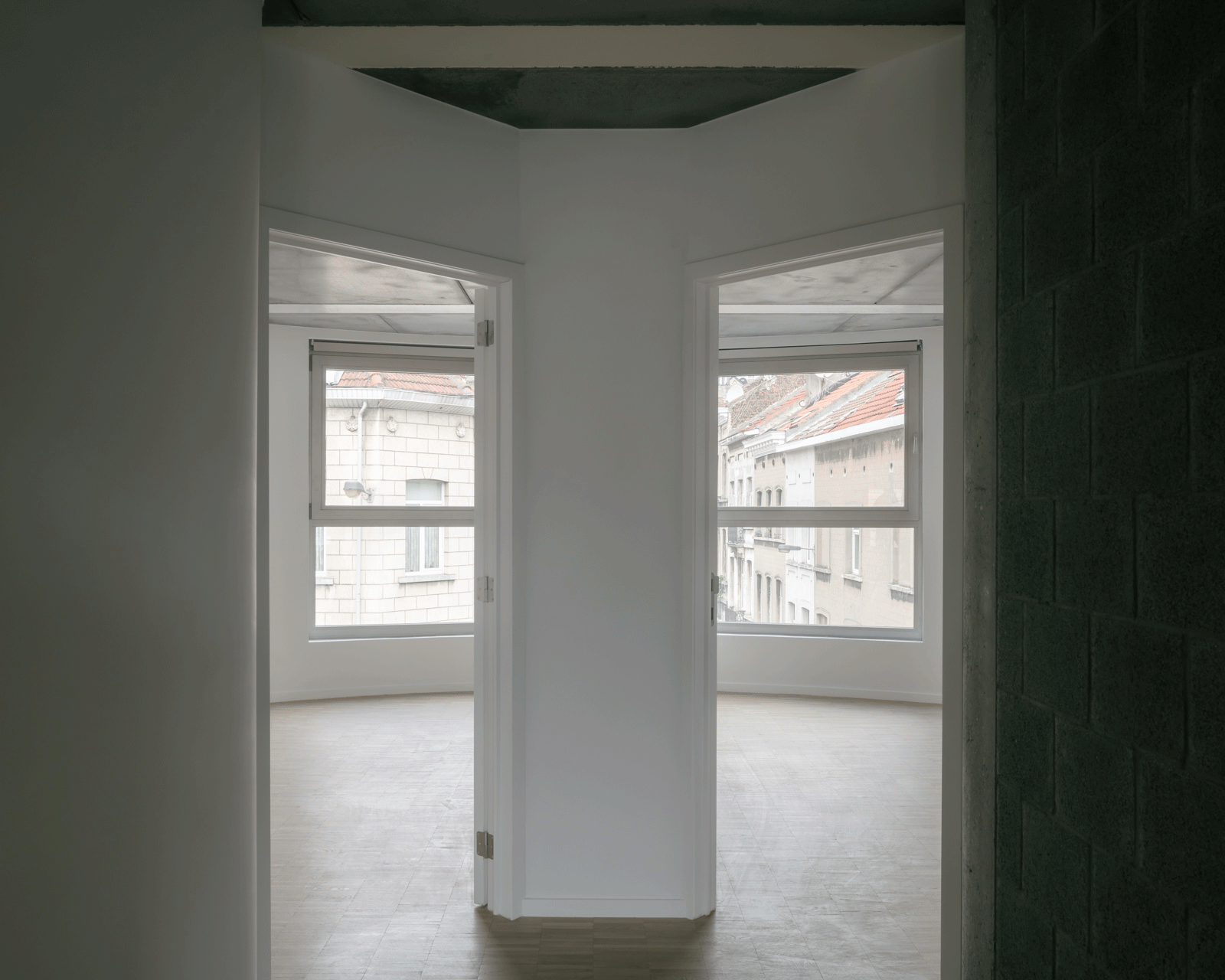 Empty room opening into a shallow bay of corner windows