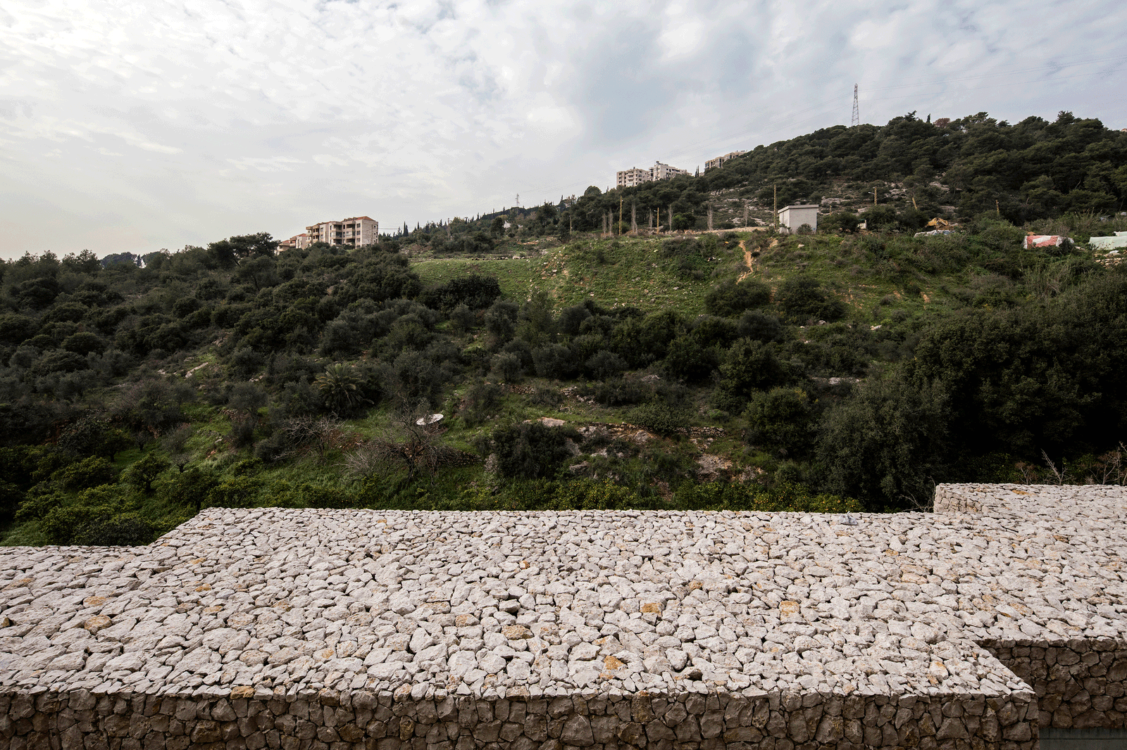 Stone roof terrace overlooking a wooded Mediterranean slope