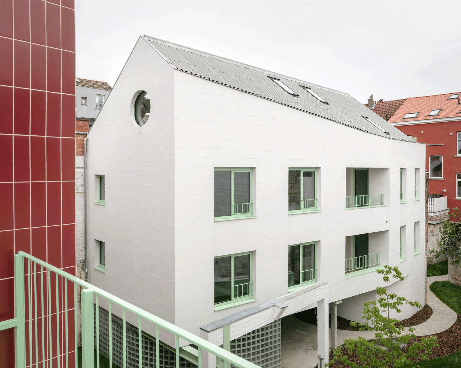 White gabled residential wing viewed from the red-tiled addition