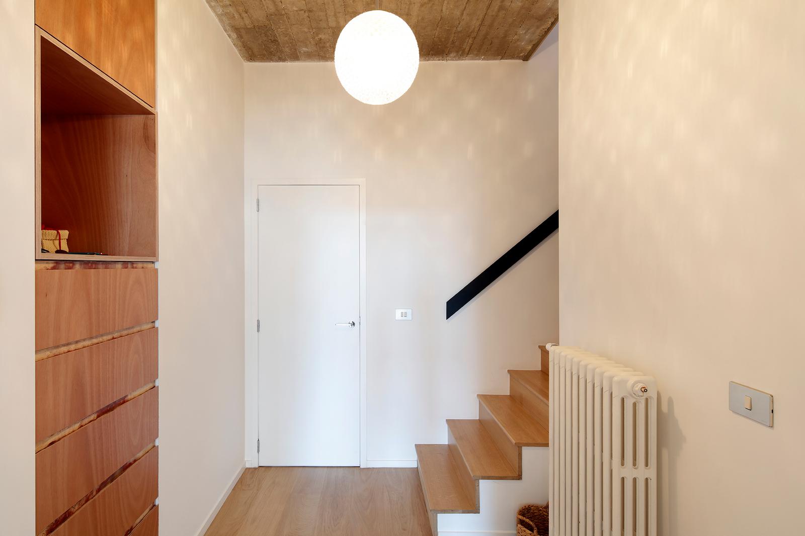 Timber stair rising beside built-in cabinetry and a white radiator