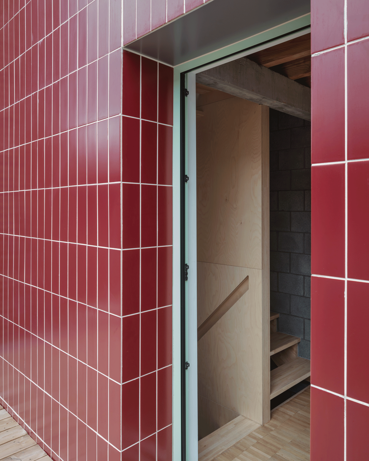 Doorway cut into a red-tiled wall with green metal trim