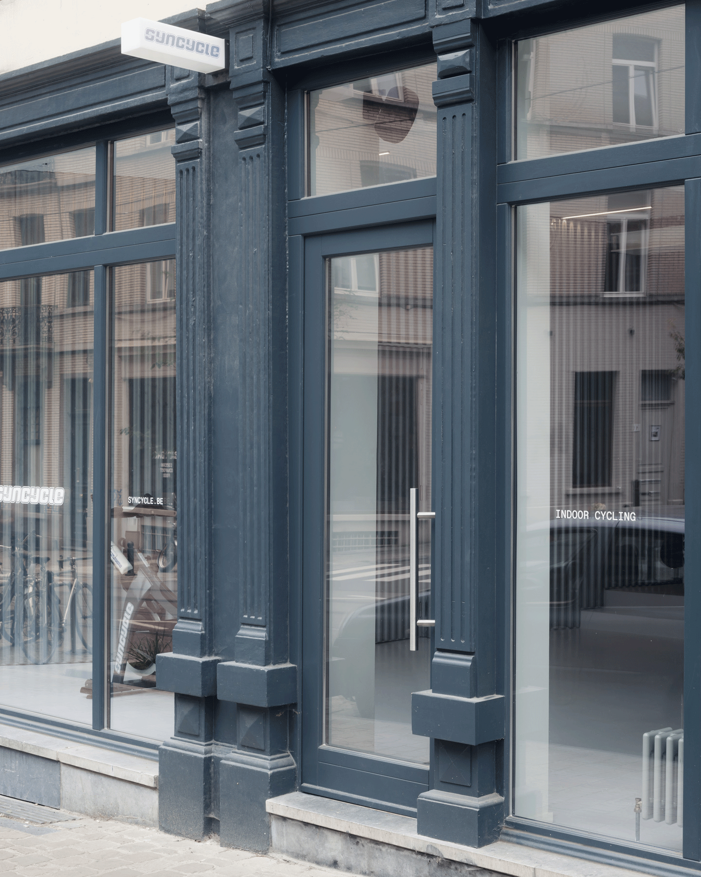 Dark blue shopfront with tall glazed doors and transom windows