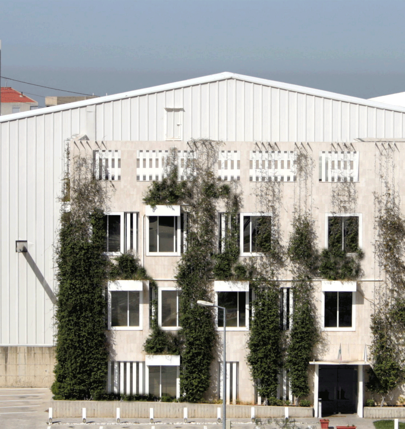 Industrial façade progressively covered by climbing vegetation