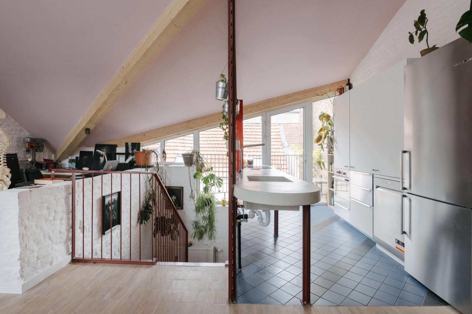 Open kitchen and living space with a red mesh partition and timber beam