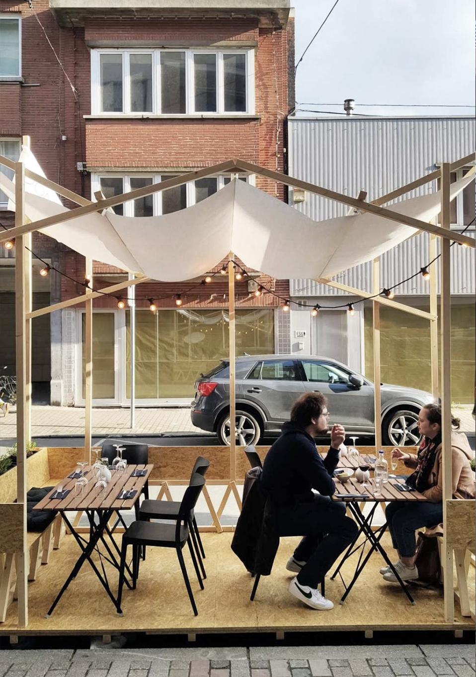 People seated beneath the fabric canopy of the timber parklet