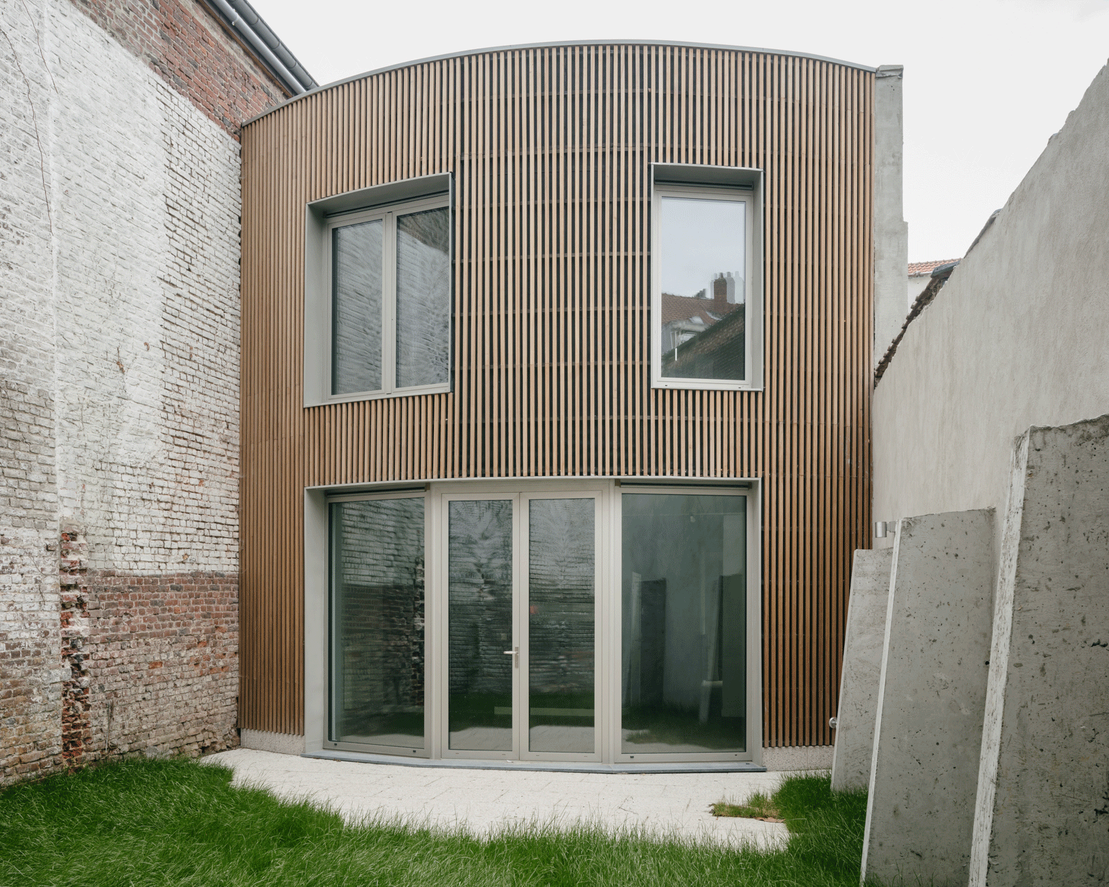 Curved timber-clad garden annex between retained masonry walls