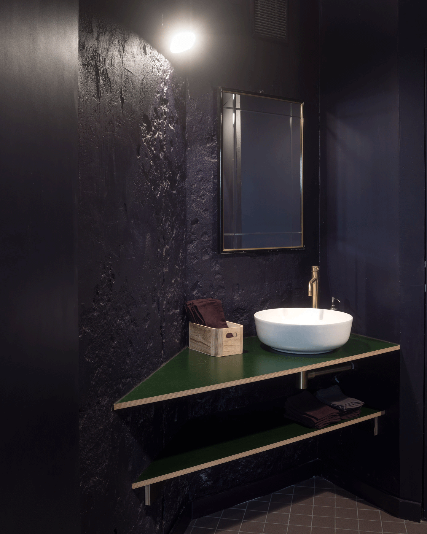 Dark washroom with a green counter and wall-mounted basin