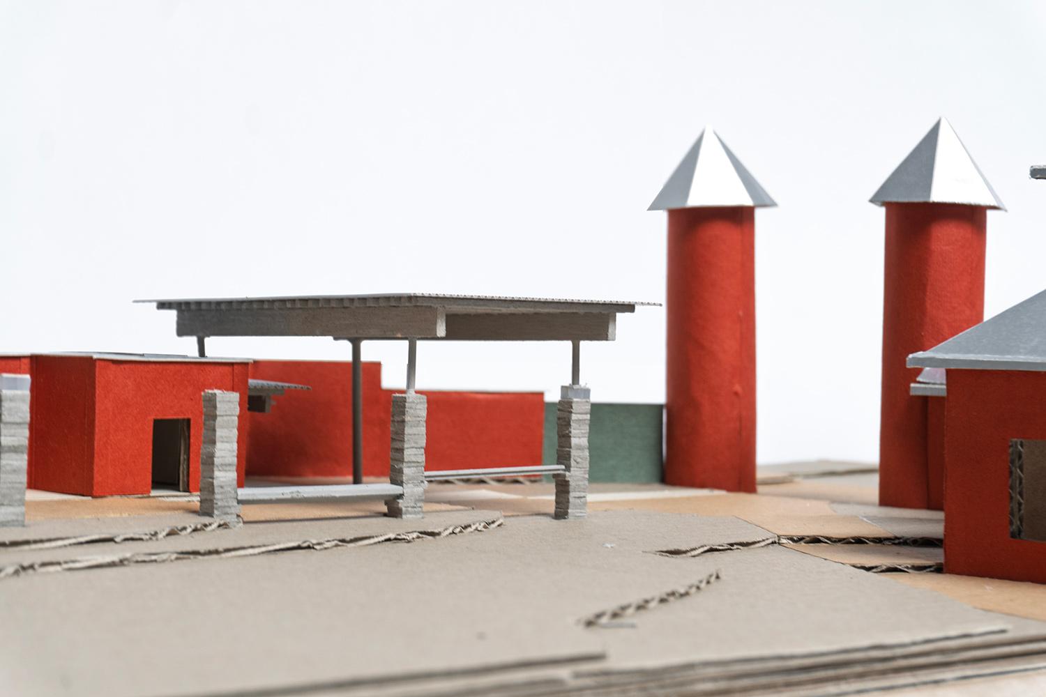 Physical model of a red masonry campus entrance with towers and canopy