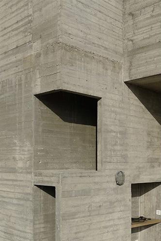 Deep window openings cut into the board-marked concrete façade