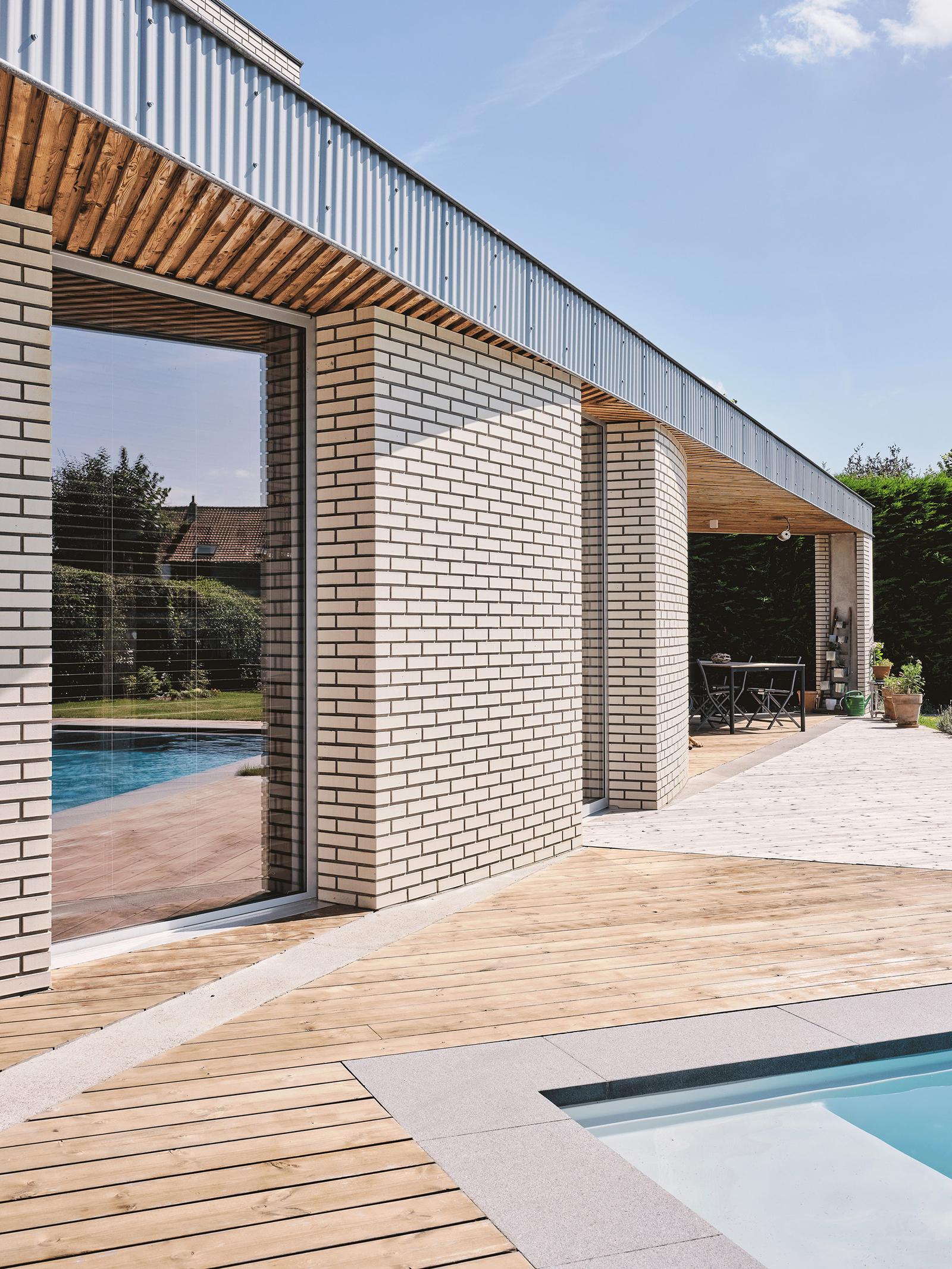Covered poolside terrace framed by brick piers and metal roofing