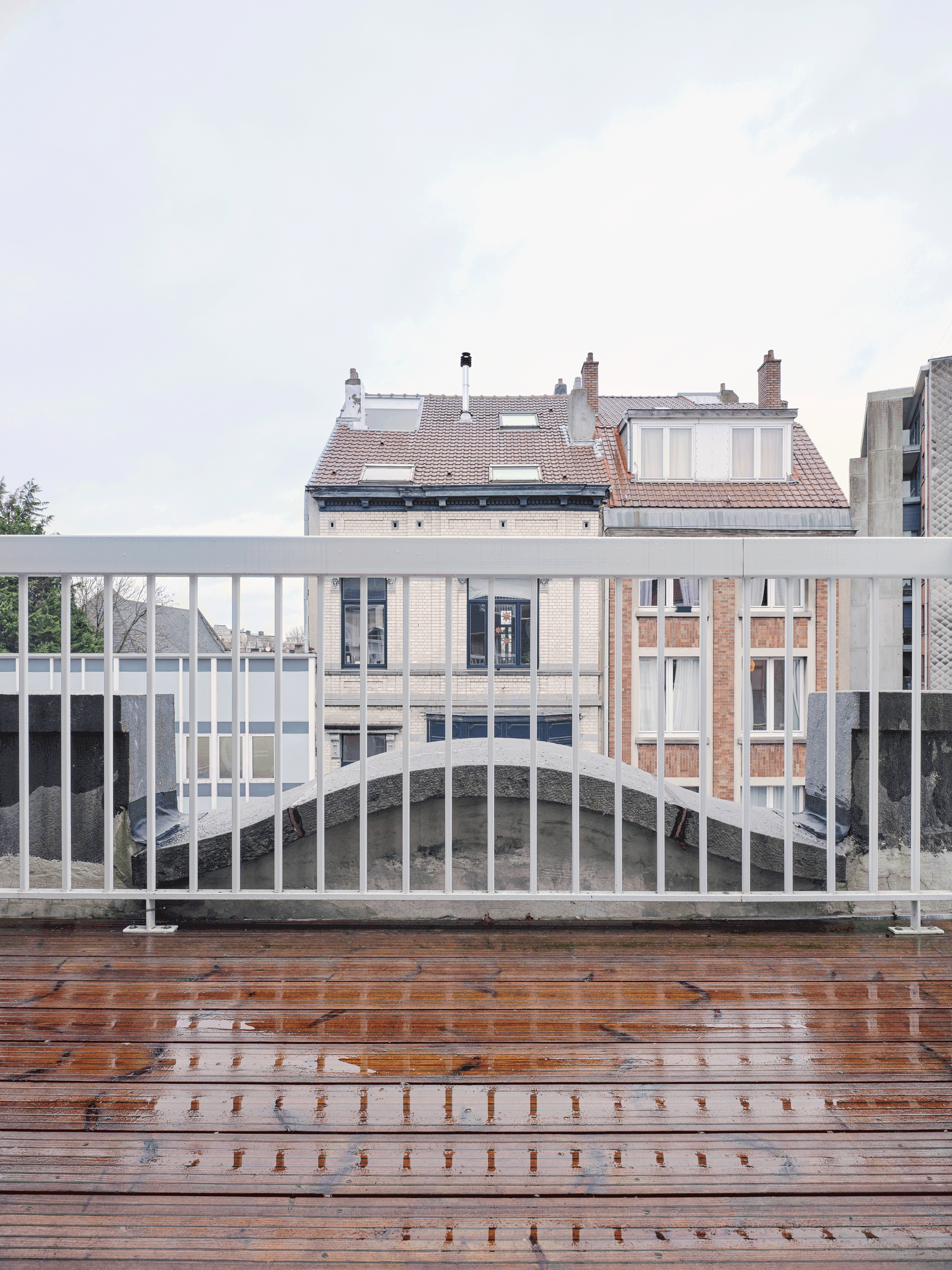 Rooftop terrace with a white railing and city buildings beyond