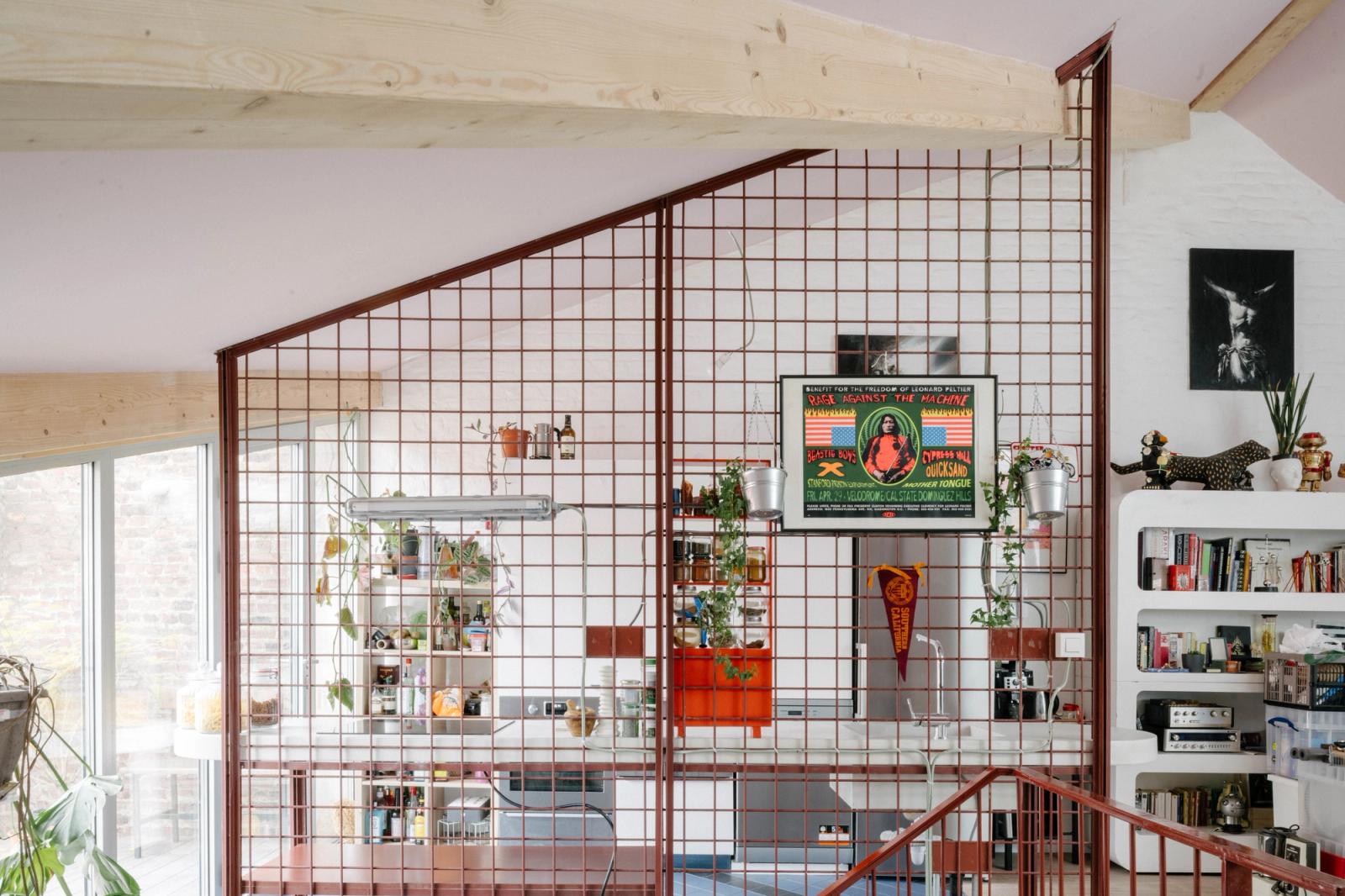 Red metal grid partition enclosing a stair in a bright living space