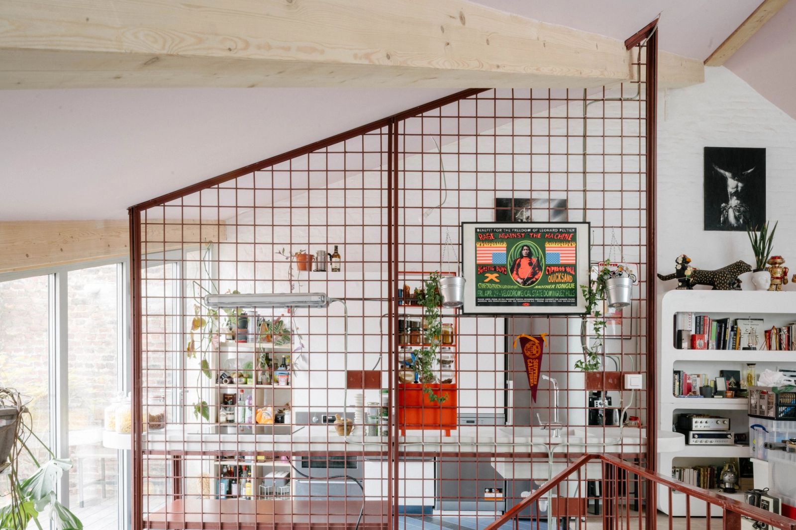 Red metal grid partition enclosing a stair in a bright living space