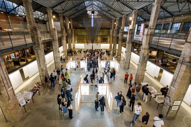 Visitors and architectural models inside a large industrial exhibition hall
