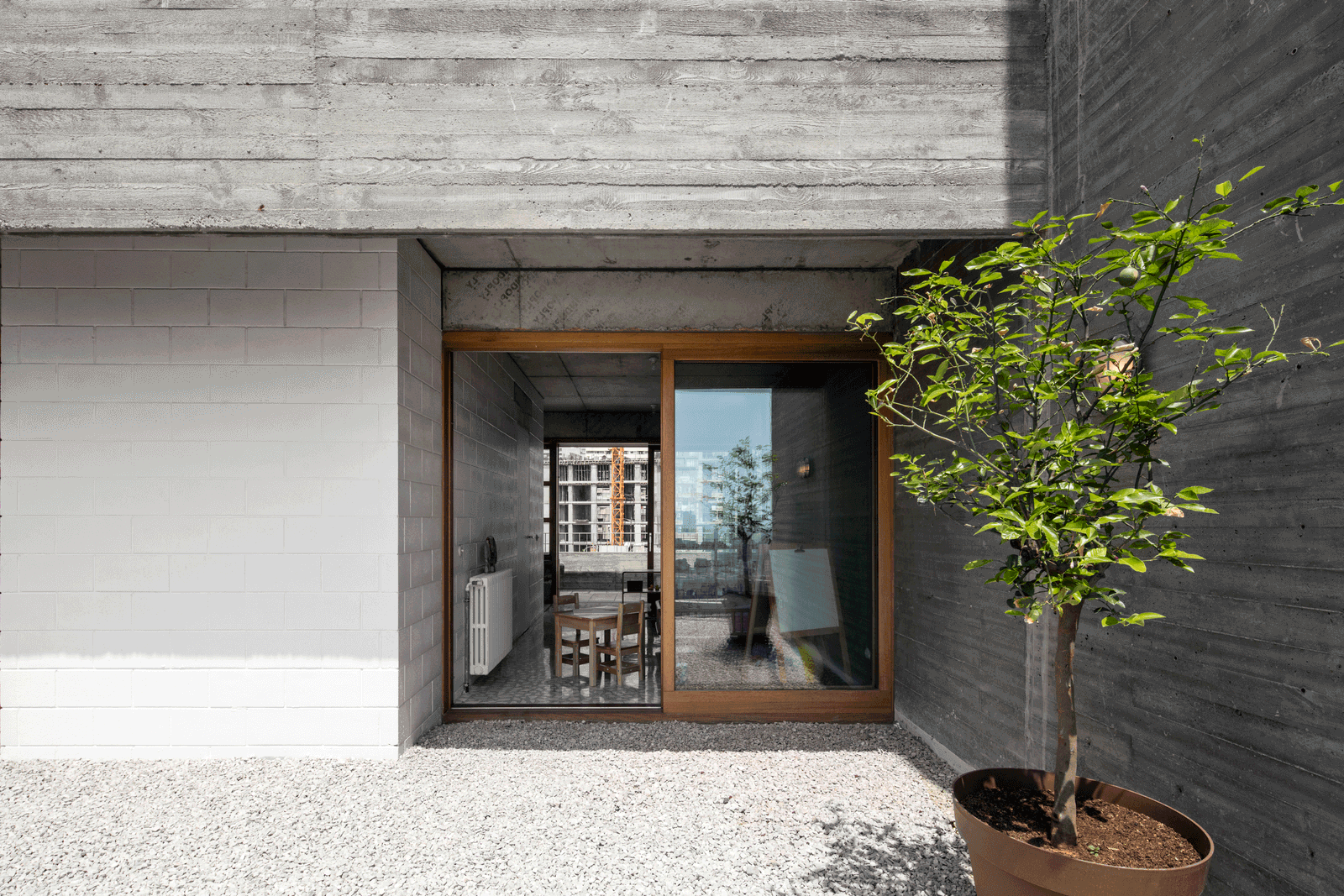 Recessed timber entrance door within board-marked concrete walls