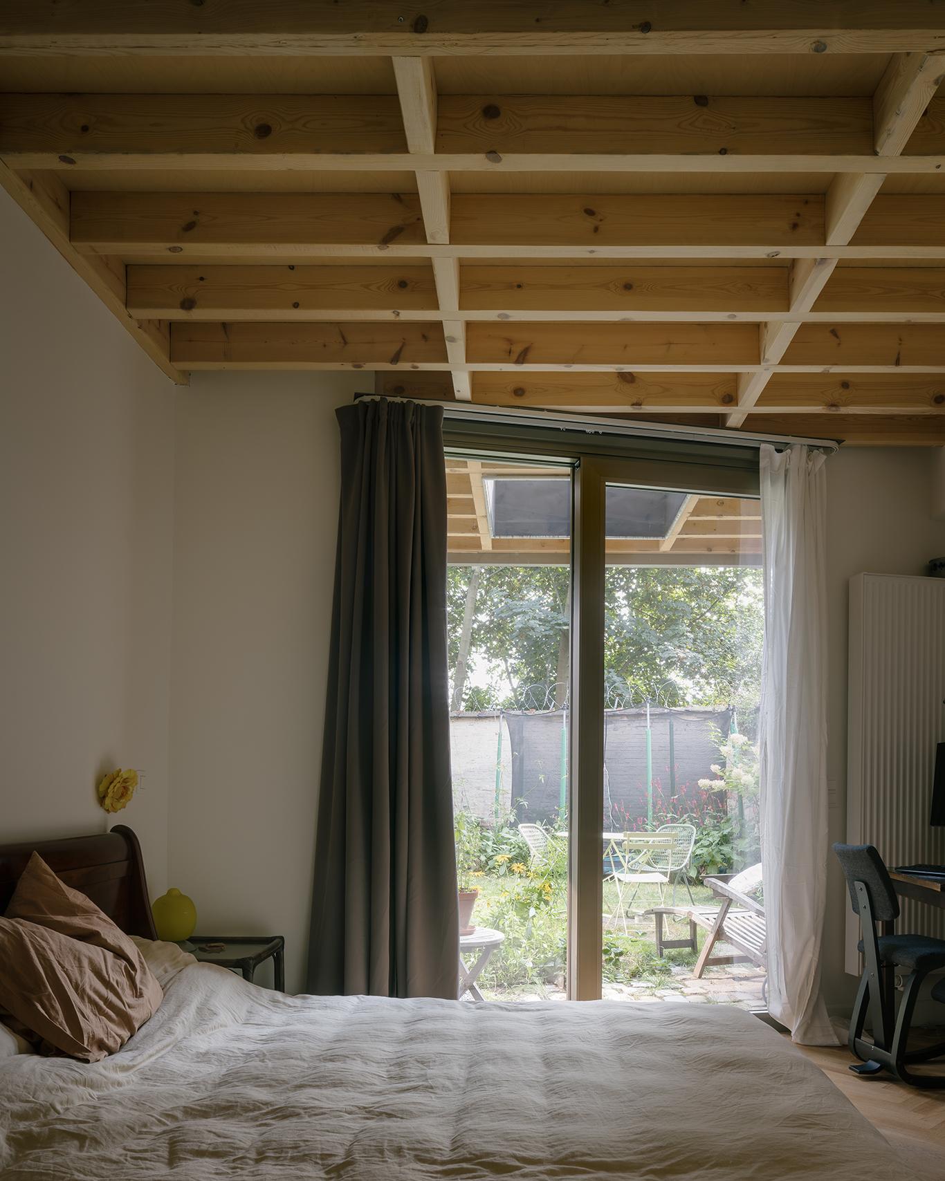 Bedroom beneath exposed timber joists with doors to the garden