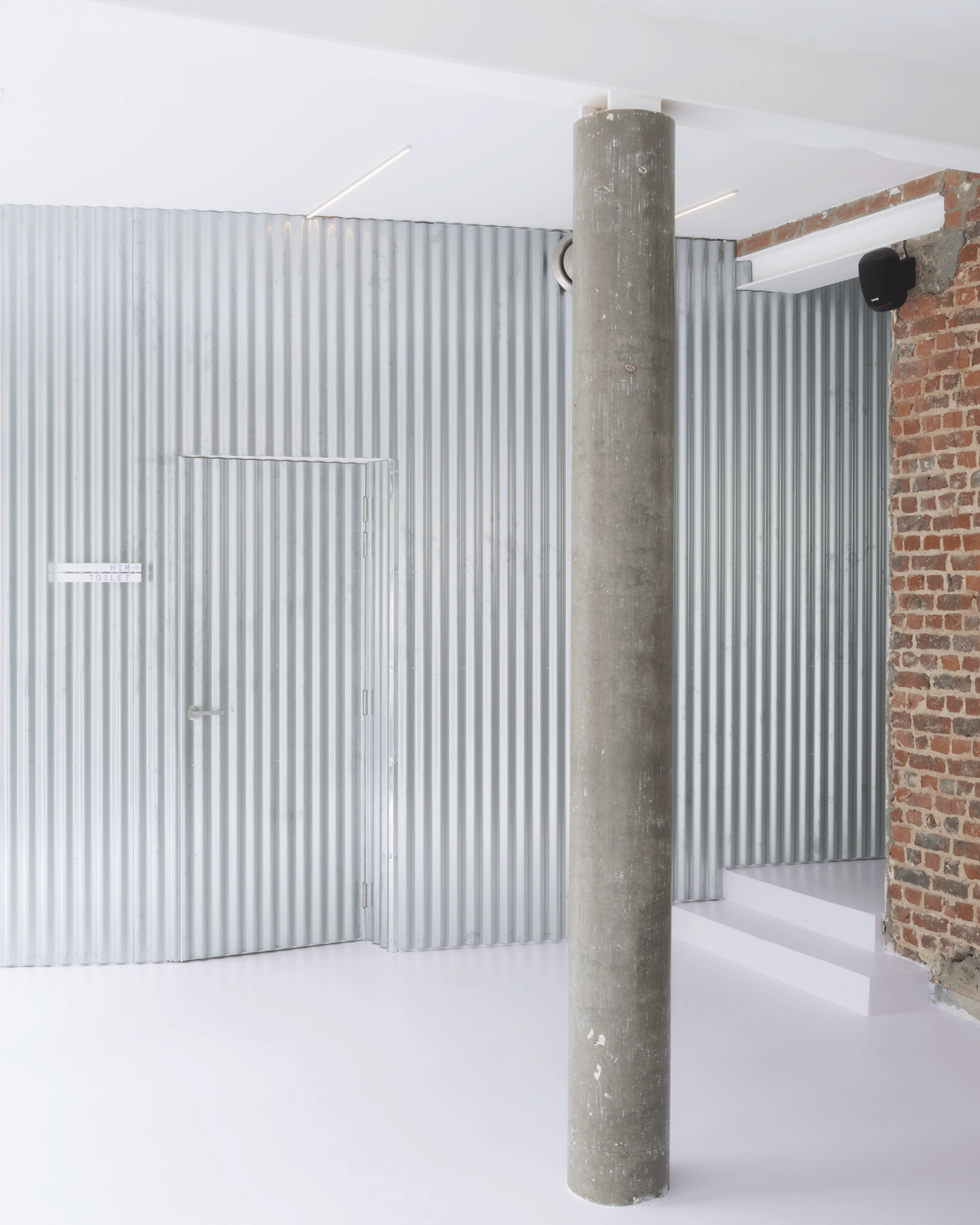 Corrugated pale wall meeting a retained concrete column