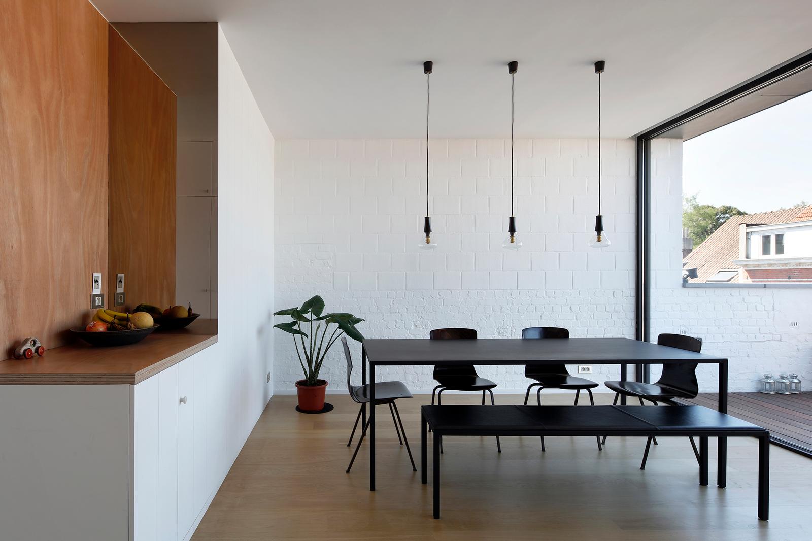 Dining area with black table, white cabinetry and terrace glazing