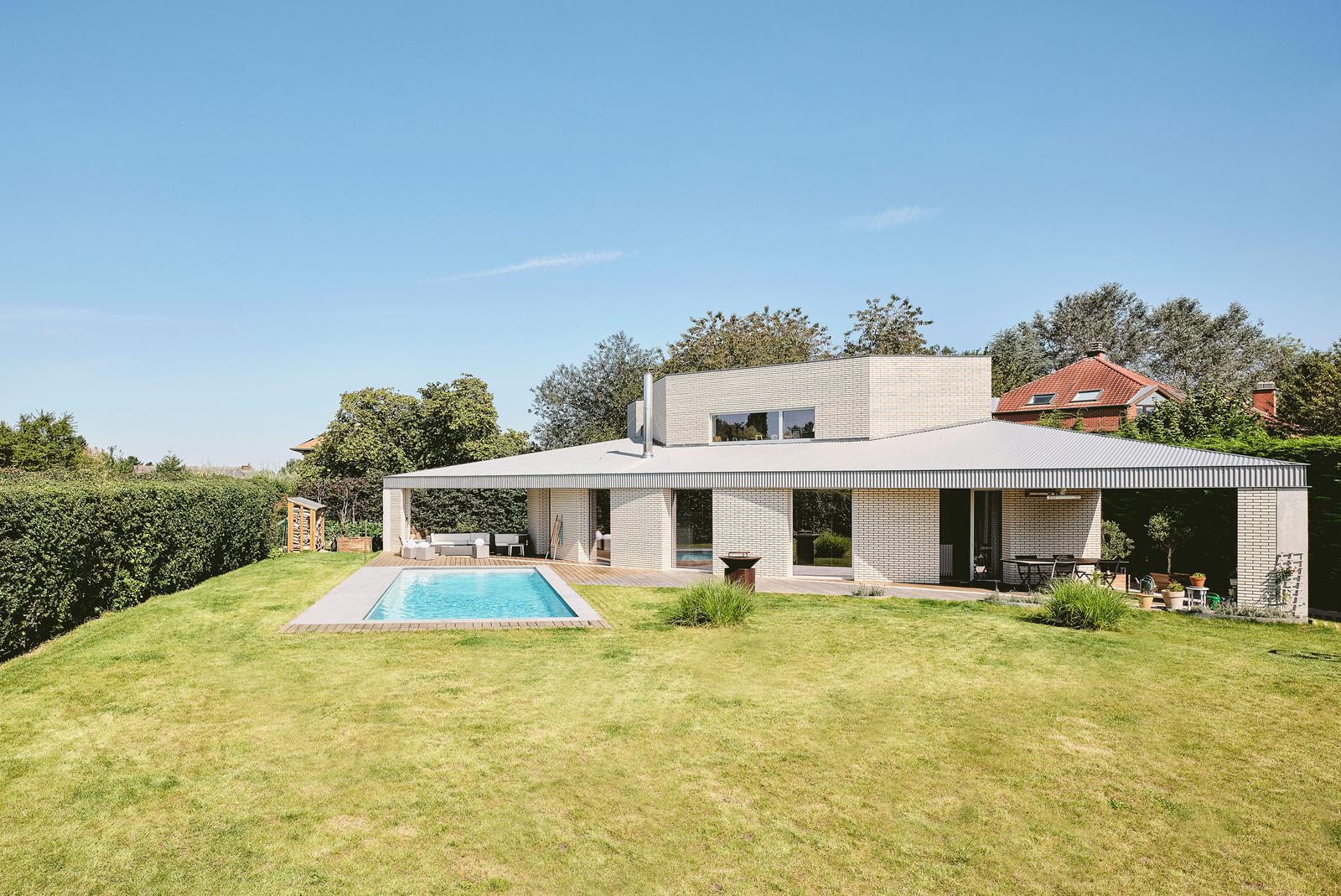 Wide lawn and pool in front of the low angular house