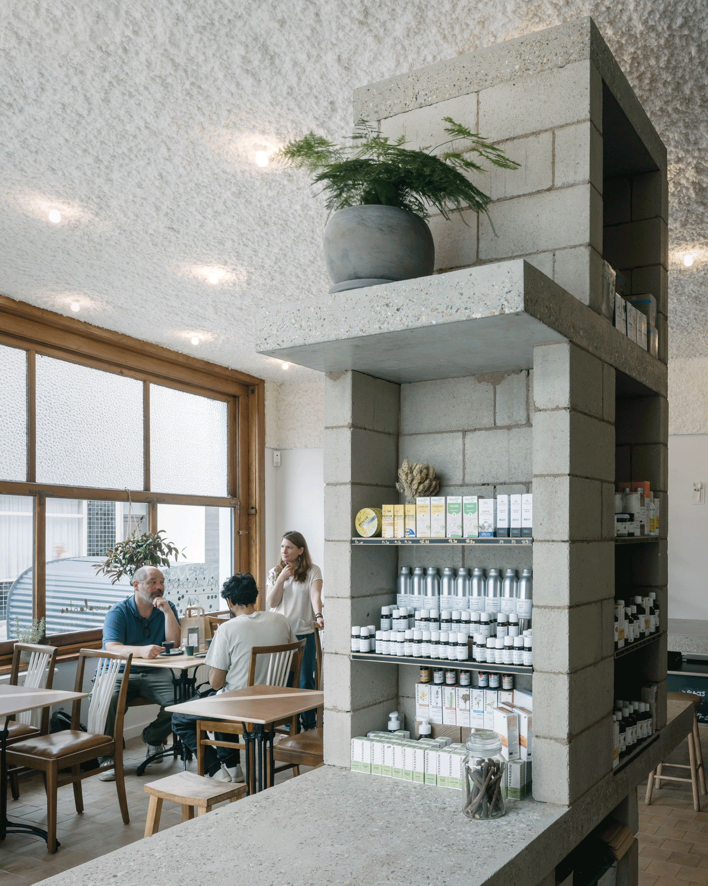 Tall terrazzo shelving dividing the shop from the communal table