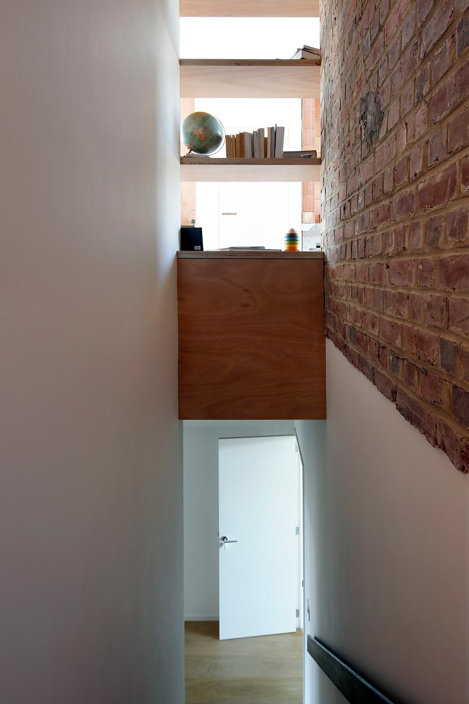 Timber stair descending beside a retained exposed brick wall