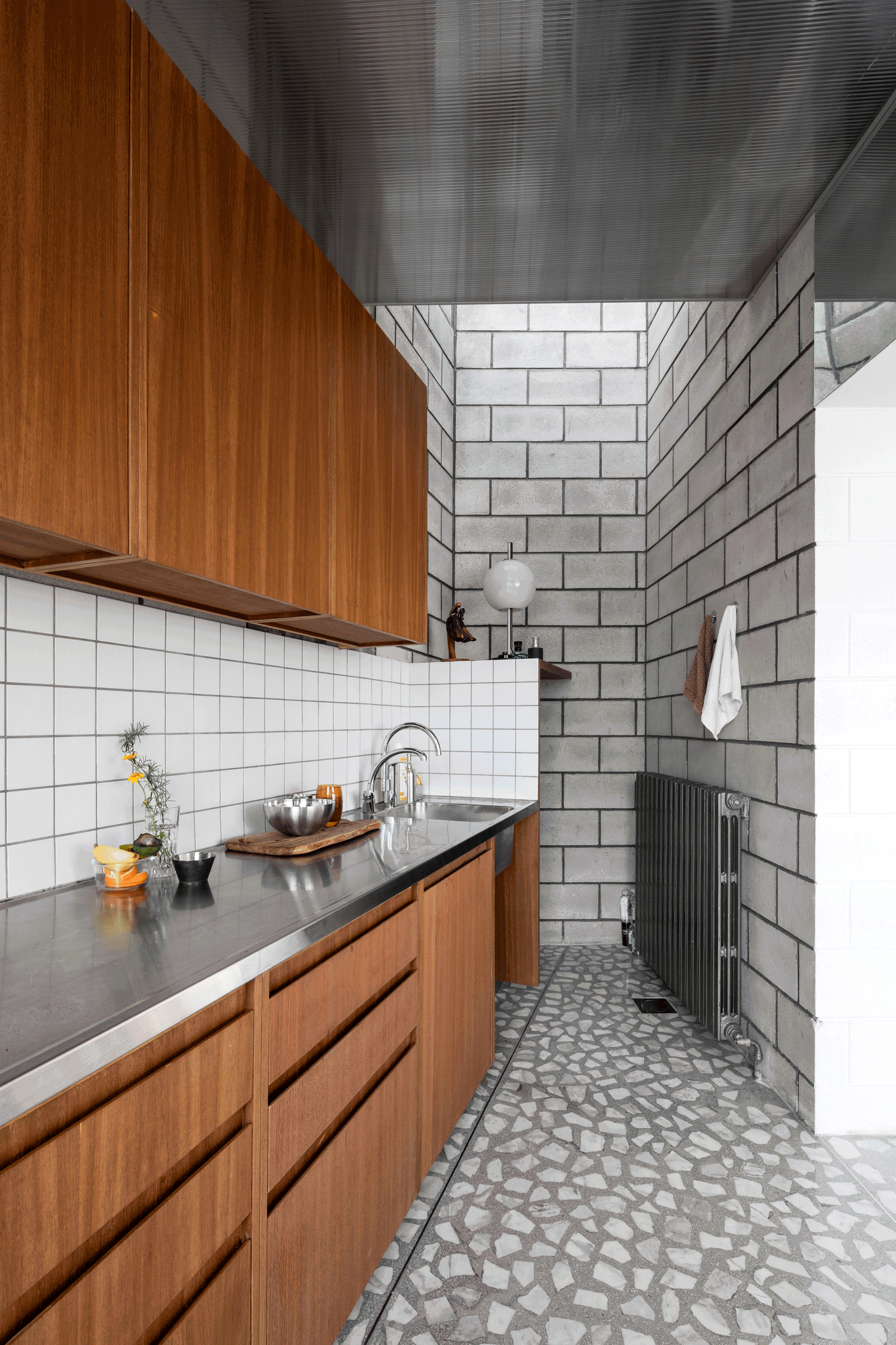 Compact kitchen with timber cabinets and white tiled block walls