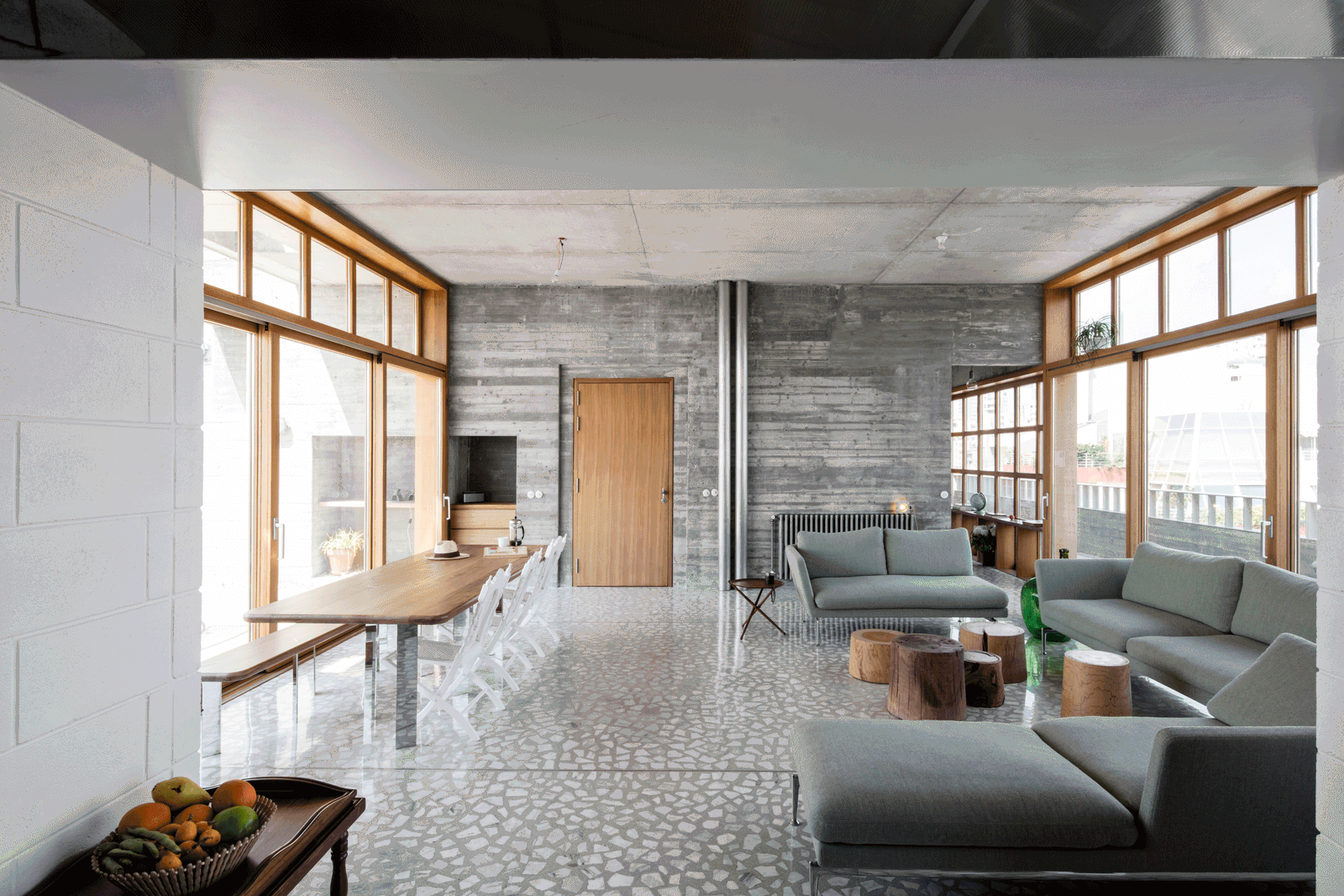 Panoramic living room wrapped by timber windows and concrete walls