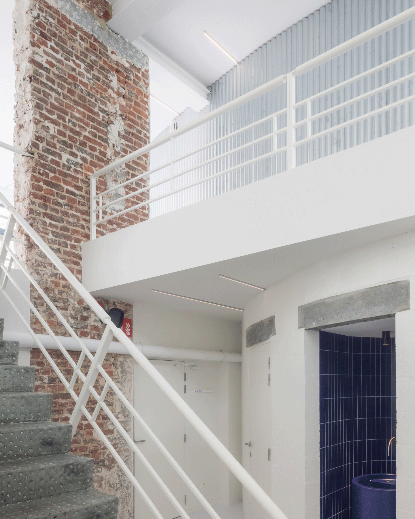 White stair and mezzanine set against retained exposed brick
