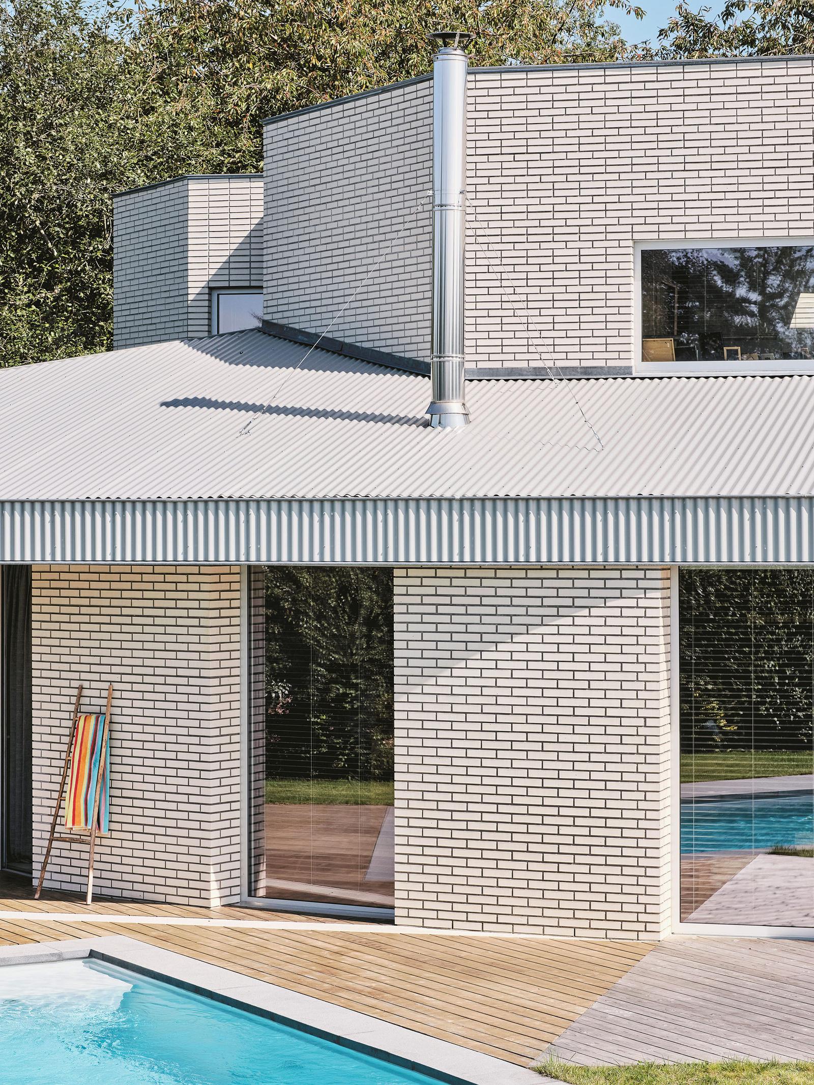 Pool courtyard framed by pale brick walls and corrugated roofing