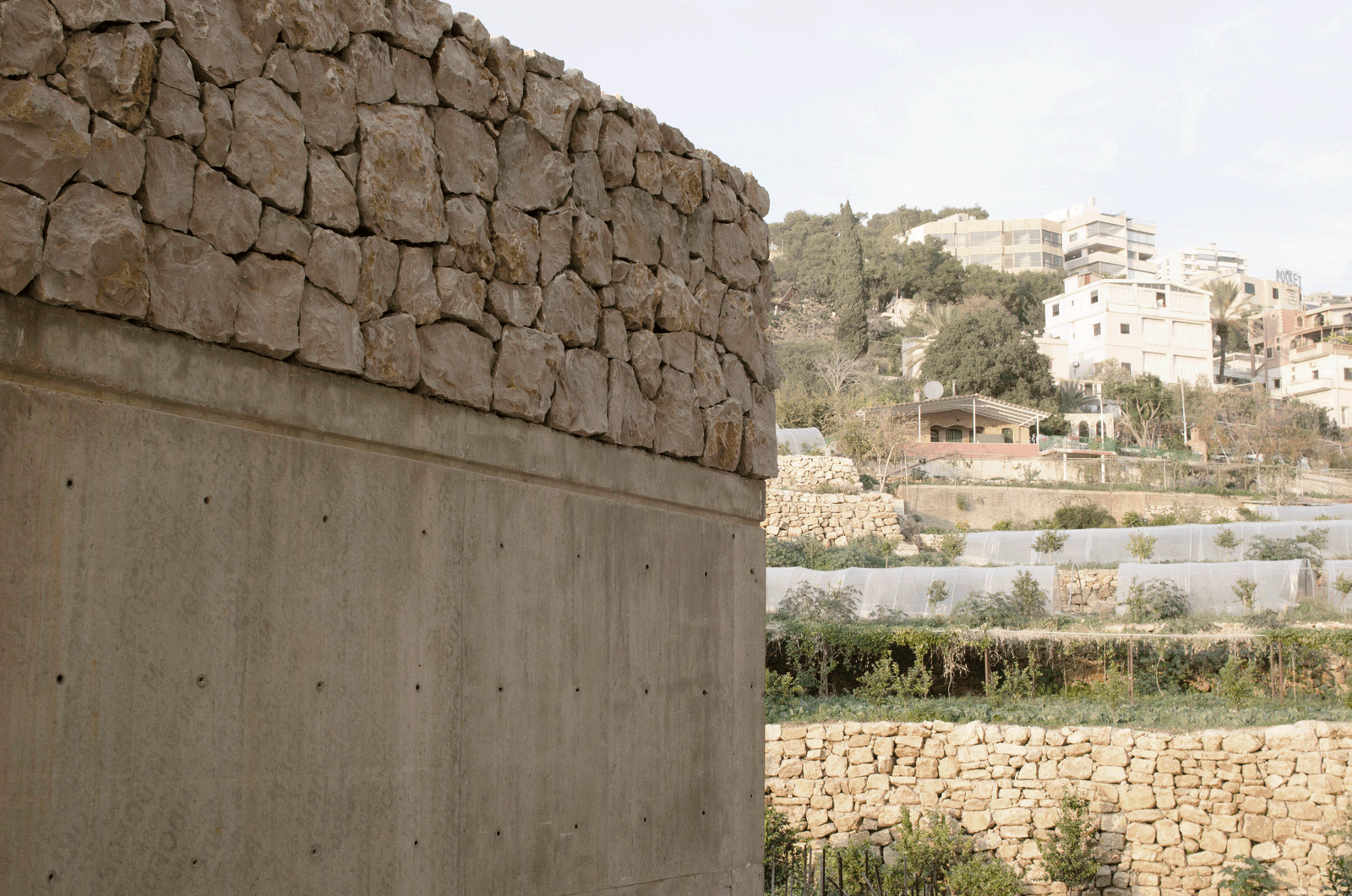 Junction of a stone parapet and concrete wall above terraced fields