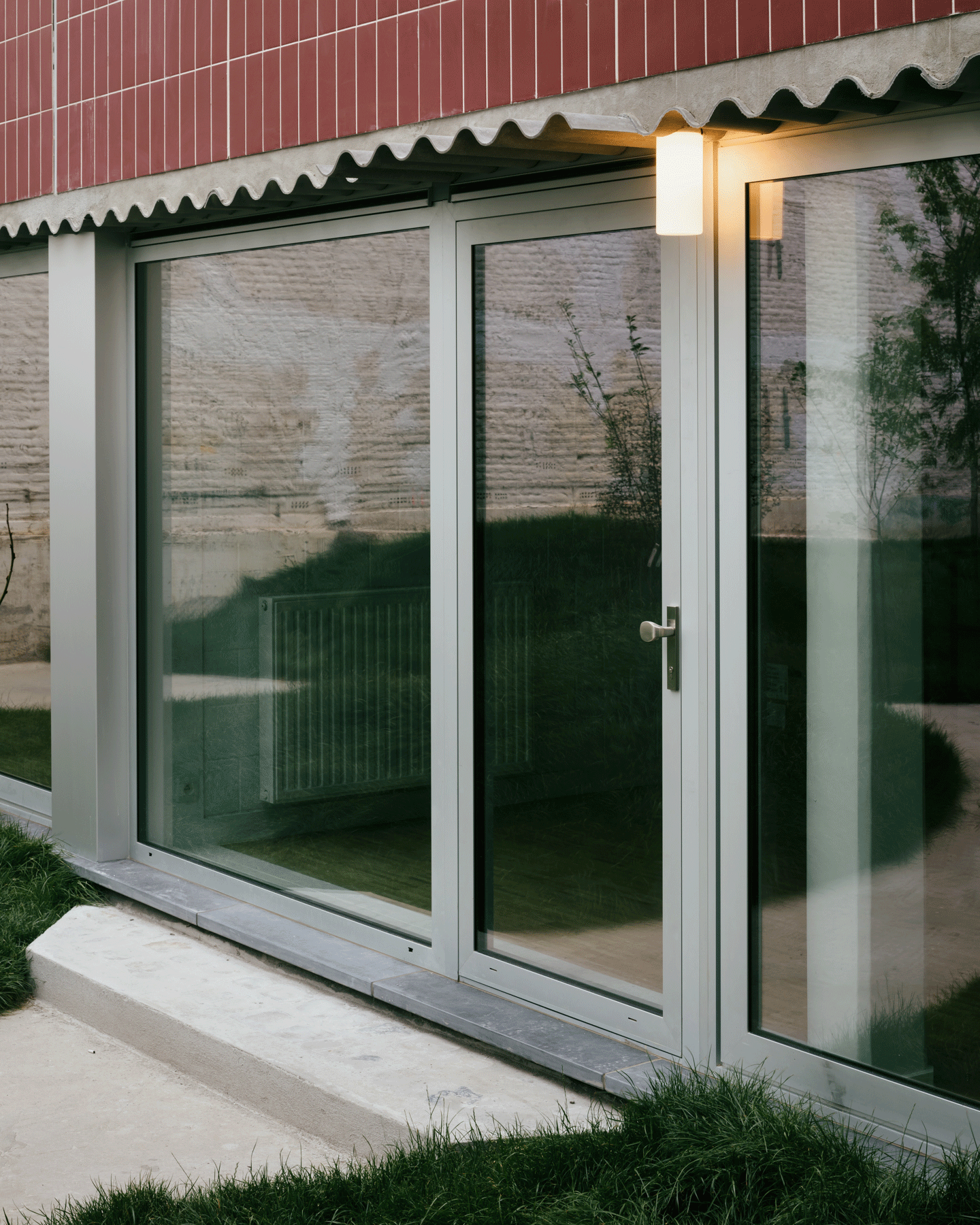 Green-framed sliding doors set into the red-tiled façade
