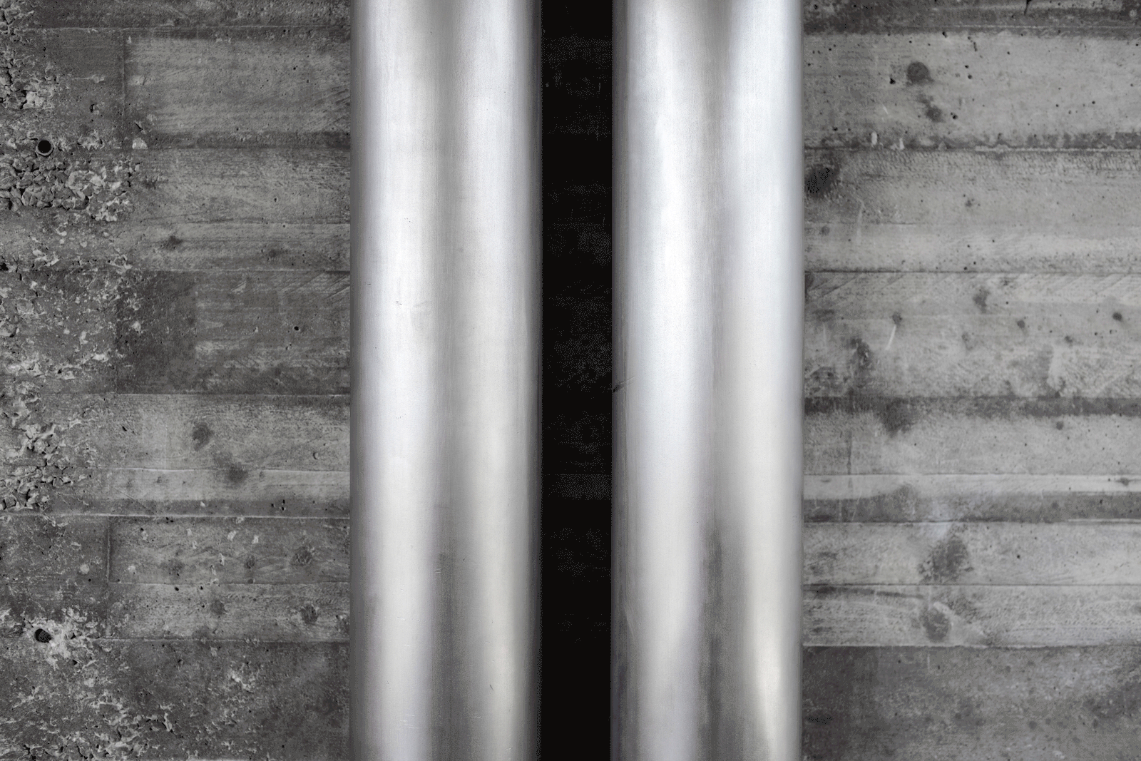 Close view of metal service pipes against board-marked concrete