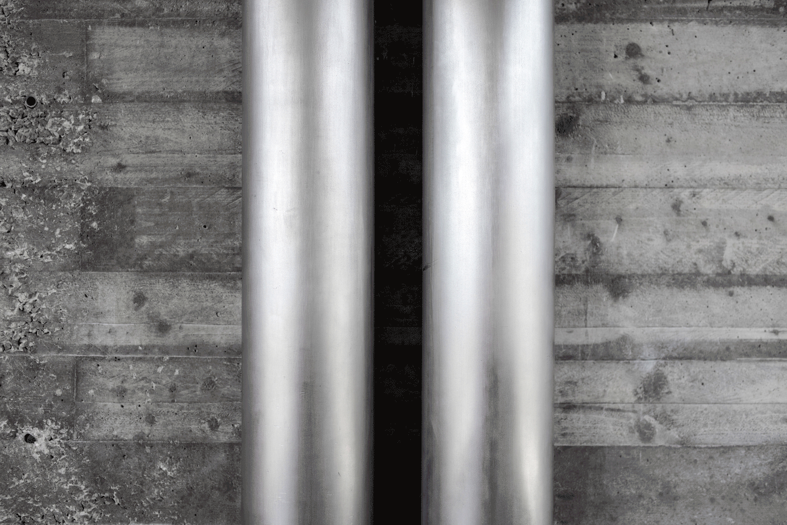 Close view of metal service pipes against board-marked concrete