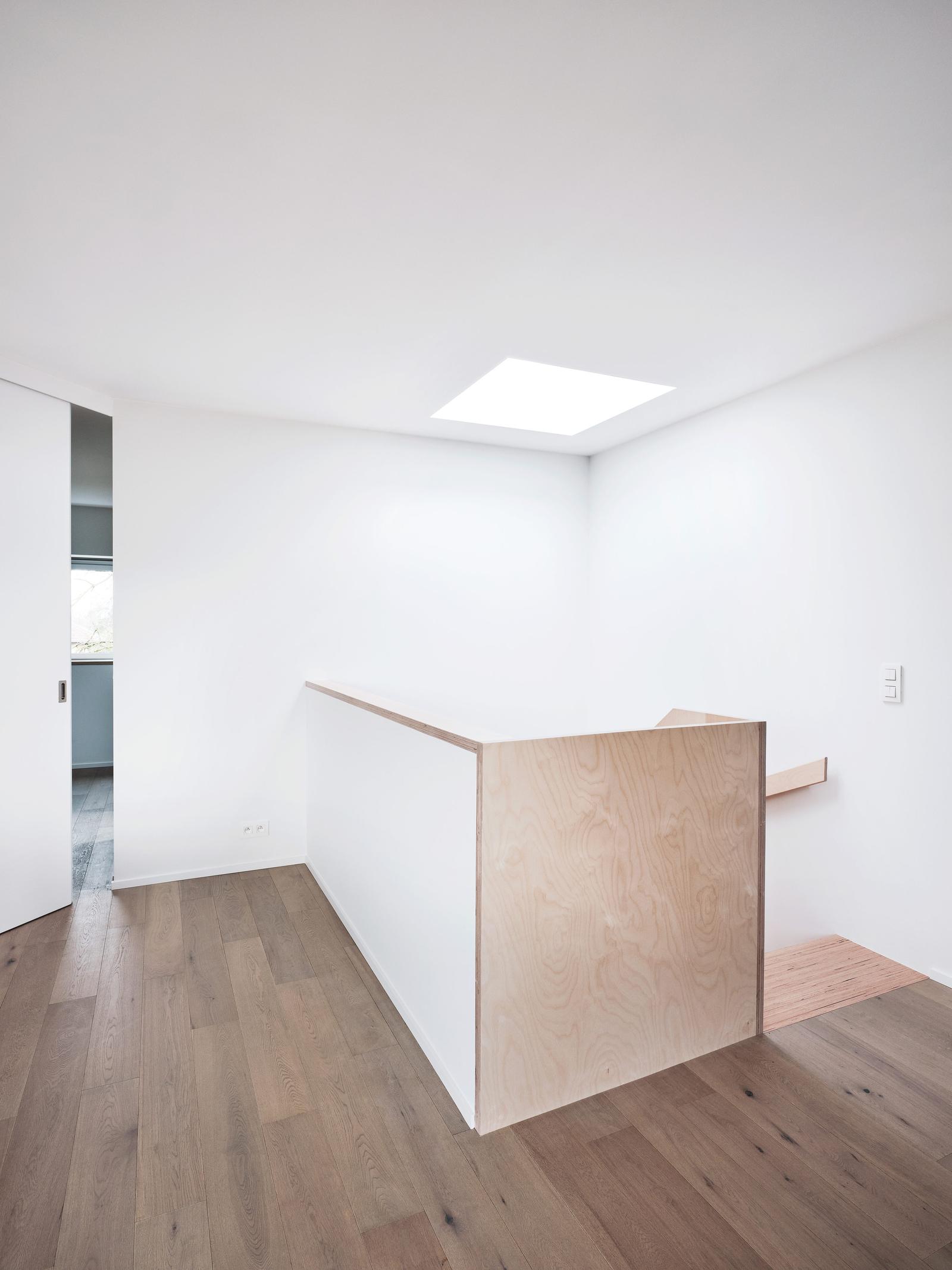 White interior landing with timber floor and a central kitchen volume