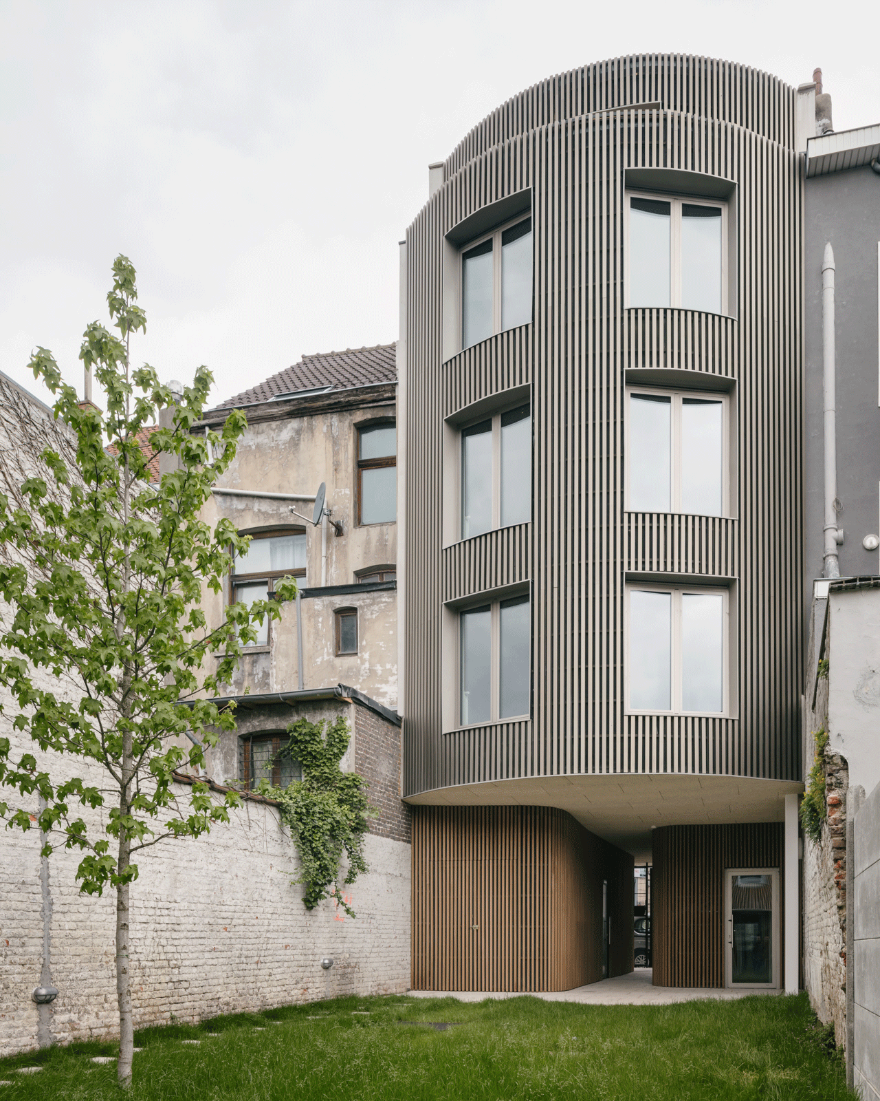 Curved garden façade wrapped in closely spaced vertical timber slats