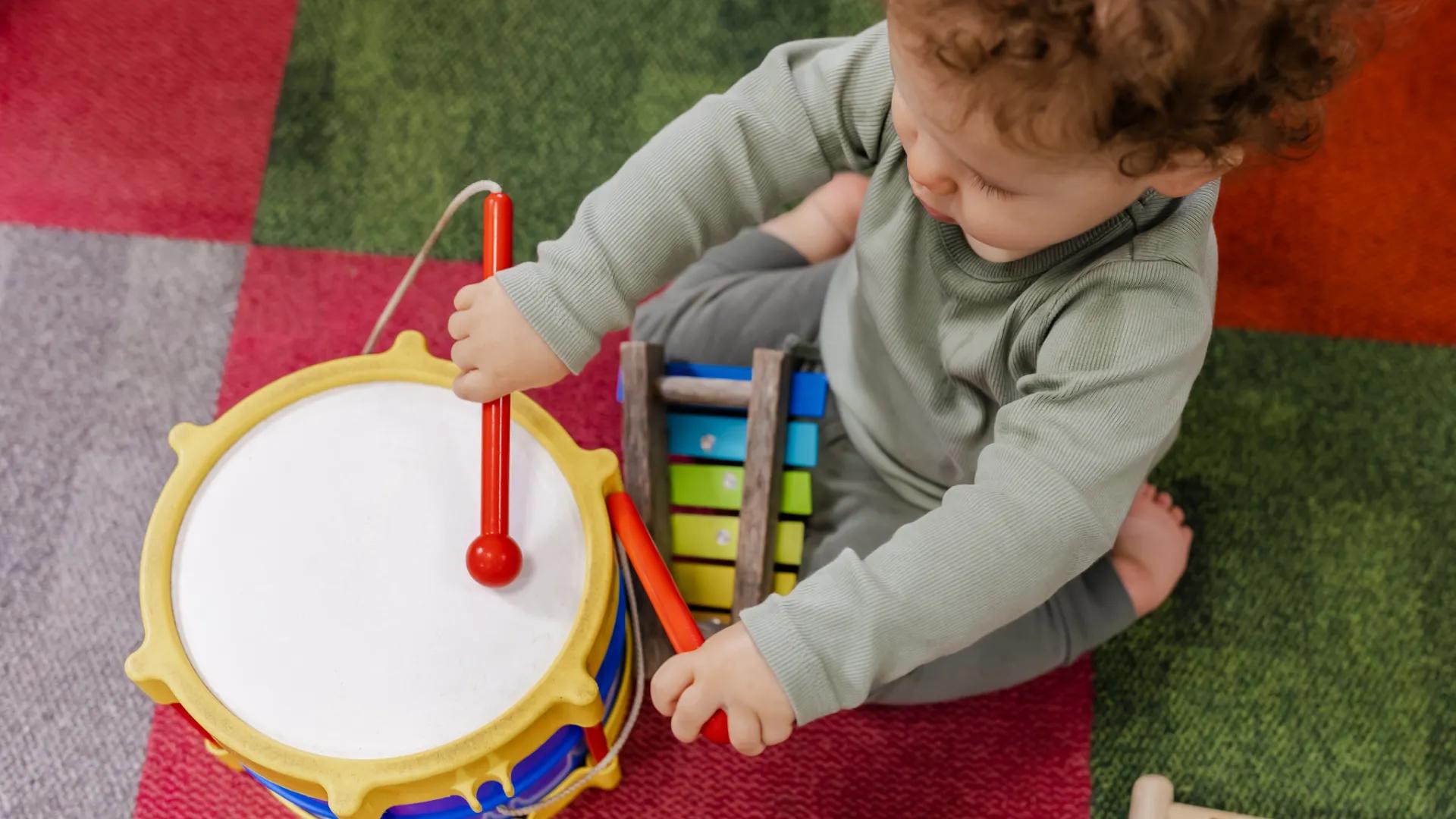 A photo of a little boy sitting, playing with a drum.