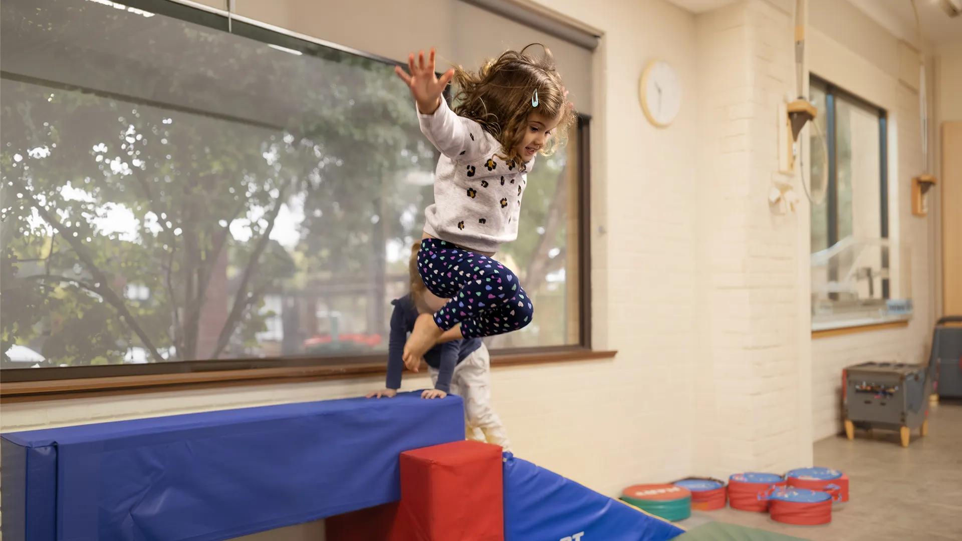 A photo of a little girl jumping off a block.